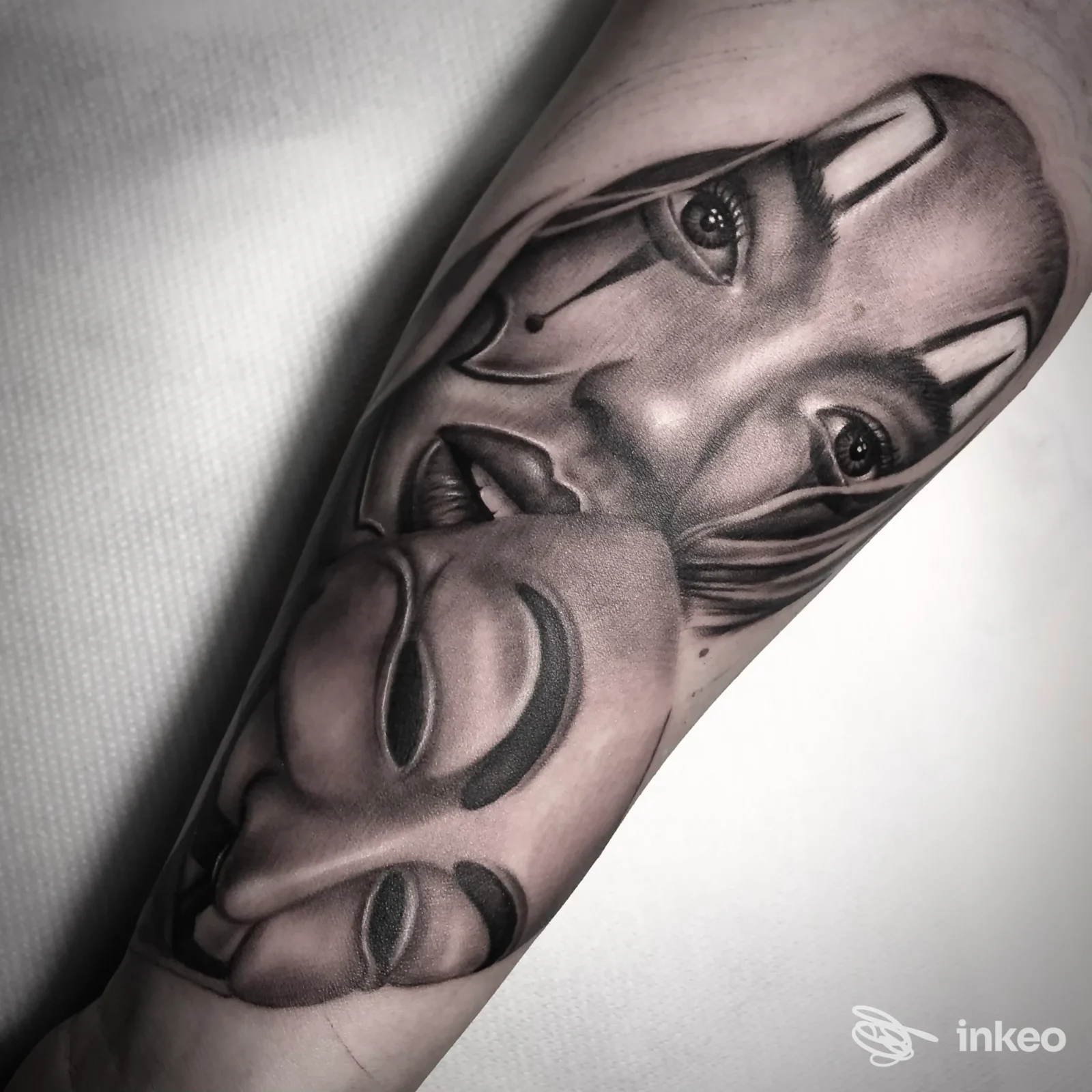 Tattoo ritratto in bianco e nero su avambraccio, raffigurante maschere.