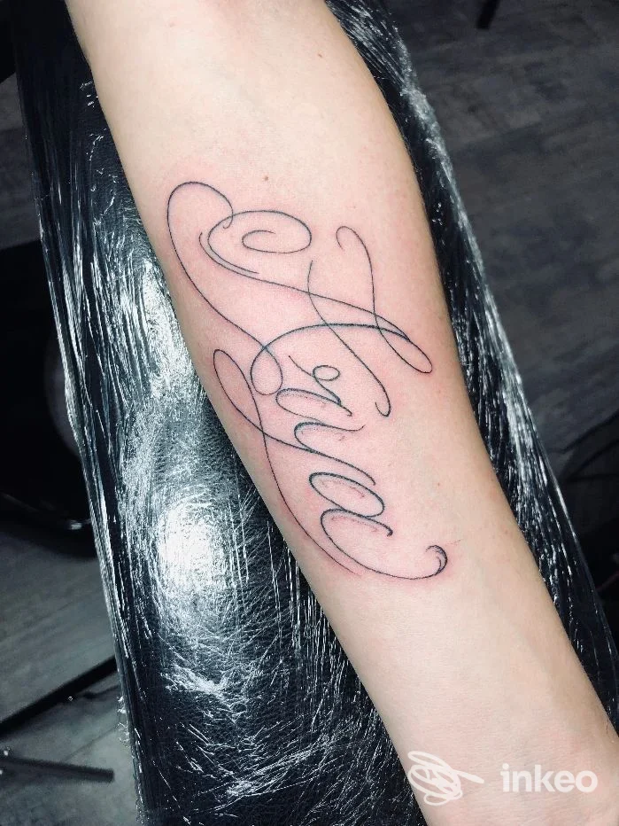 Tatuaggio calligrafico a inchiostro nero visibile sull'avambraccio, foto fornita da Enola Tattoo e Piercing, Pontecorvo.