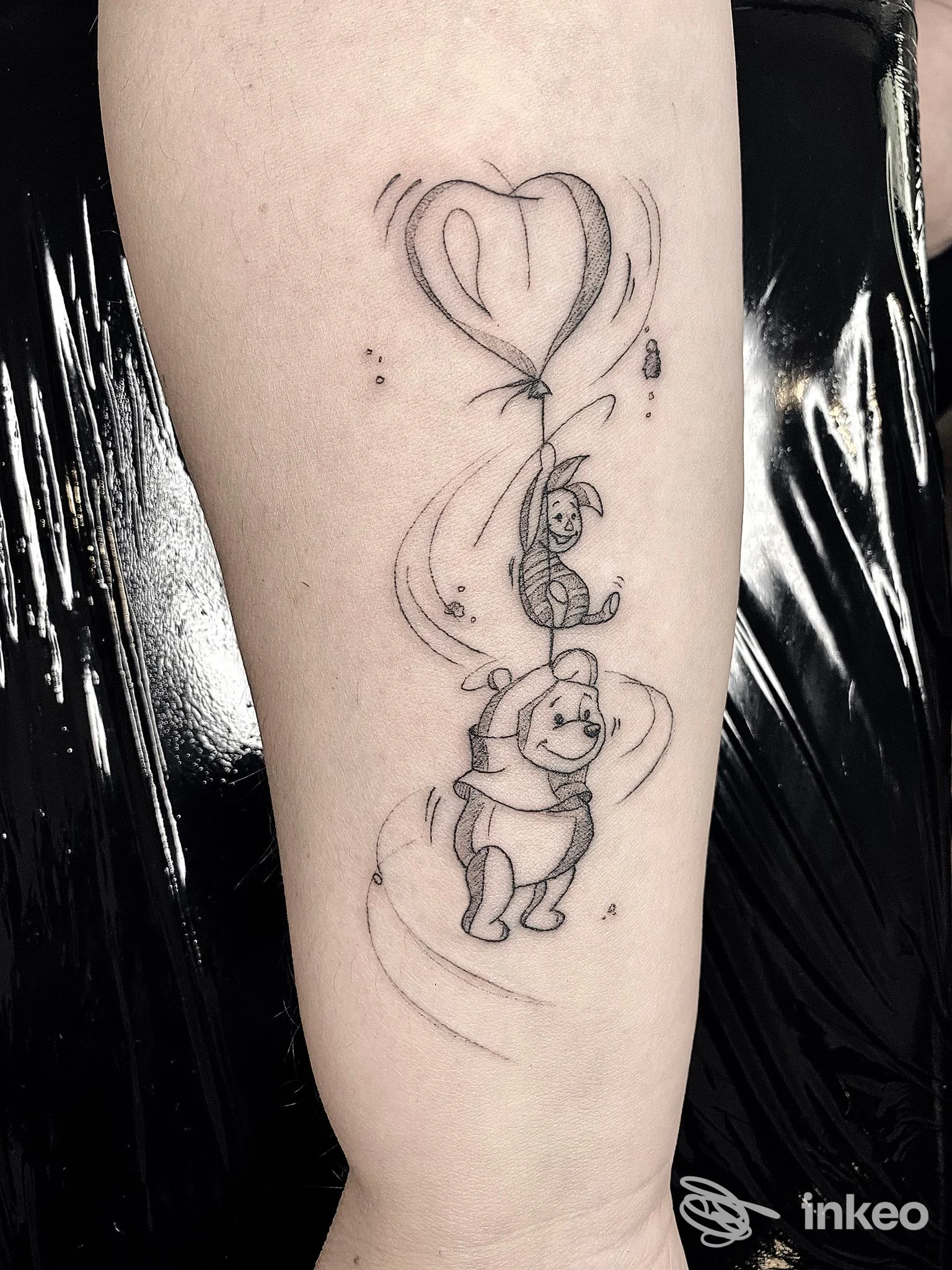Tatuaggio in linea nera su avambraccio con Winnie the Pooh e un amico sospesi a un palloncino a cuore — Enrico Marconi Tattoo, Roma.
