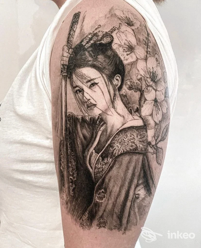 Tatuaggio realistico su braccio superiore raffigurante una donna in stile orientale con fiori, realizzato da Enrico Marconi Tattoo, Roma.