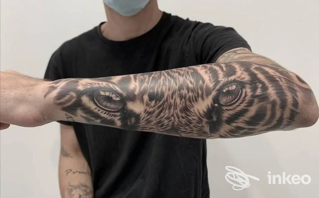 Tatuaggio realistico con occhi di tigre sull'avambraccio, foto fornita da Free Hand Tattoo di Simone Scarcioni, Roma.