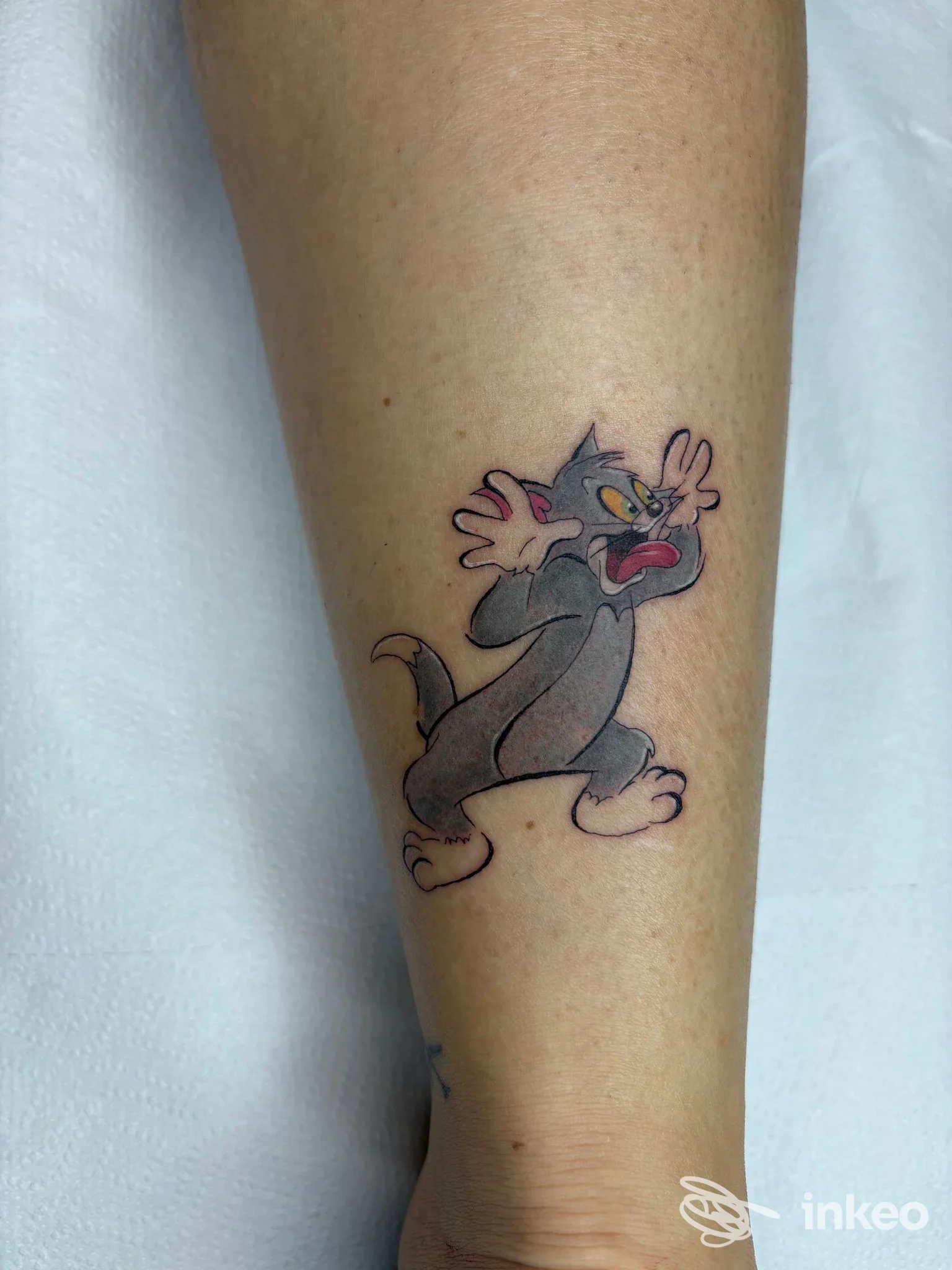 Tatuaggio in stile cartoon raffigurante Tom sul polpaccio, linee nette e colori pieni, realizzato da Floreiki Tattoo a Roma.