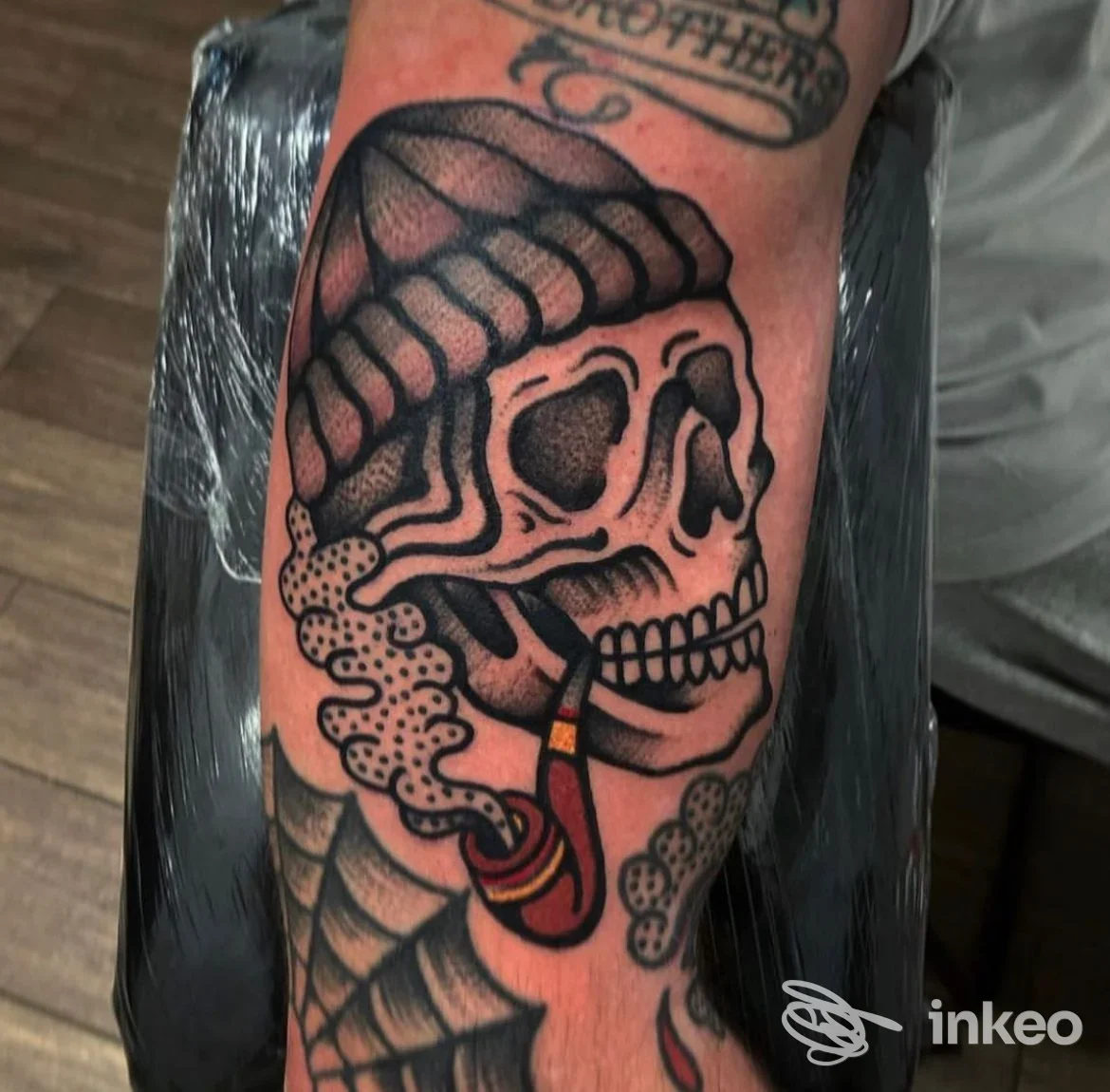 Tatuaggio su avambraccio raffigurante teschio con berretto e pipa, realizzato da Hard Work Tattoo a Roma.