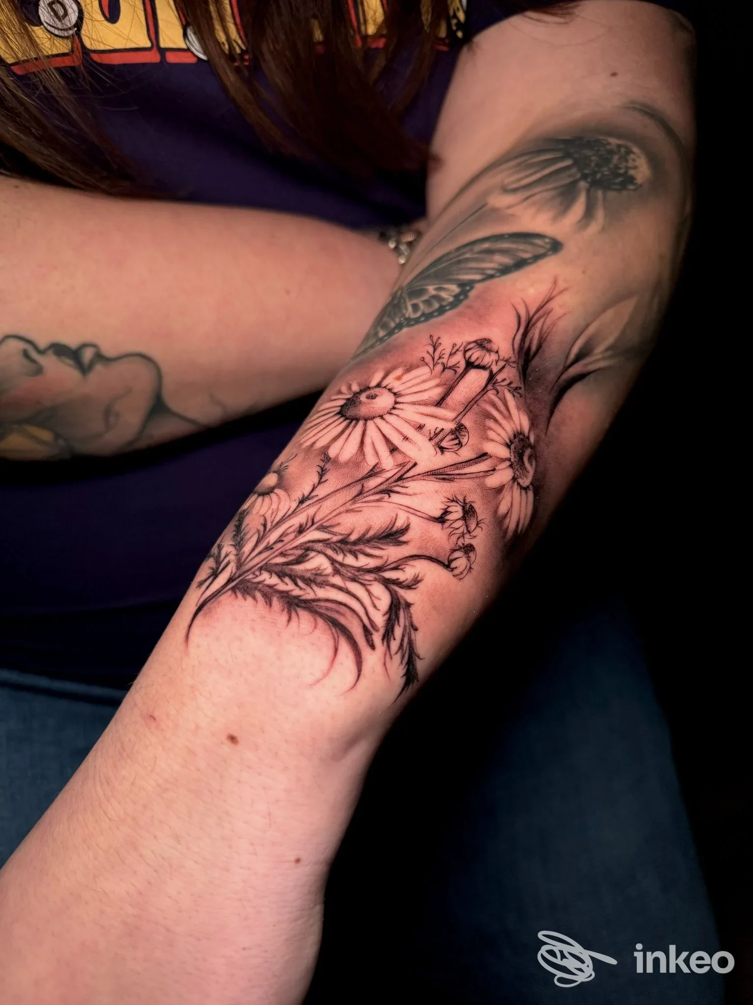 Tatuaggio floreale in bianco e nero con margherite sull'avambraccio, foto fornita da Hera Tattoo Studio, Roma.