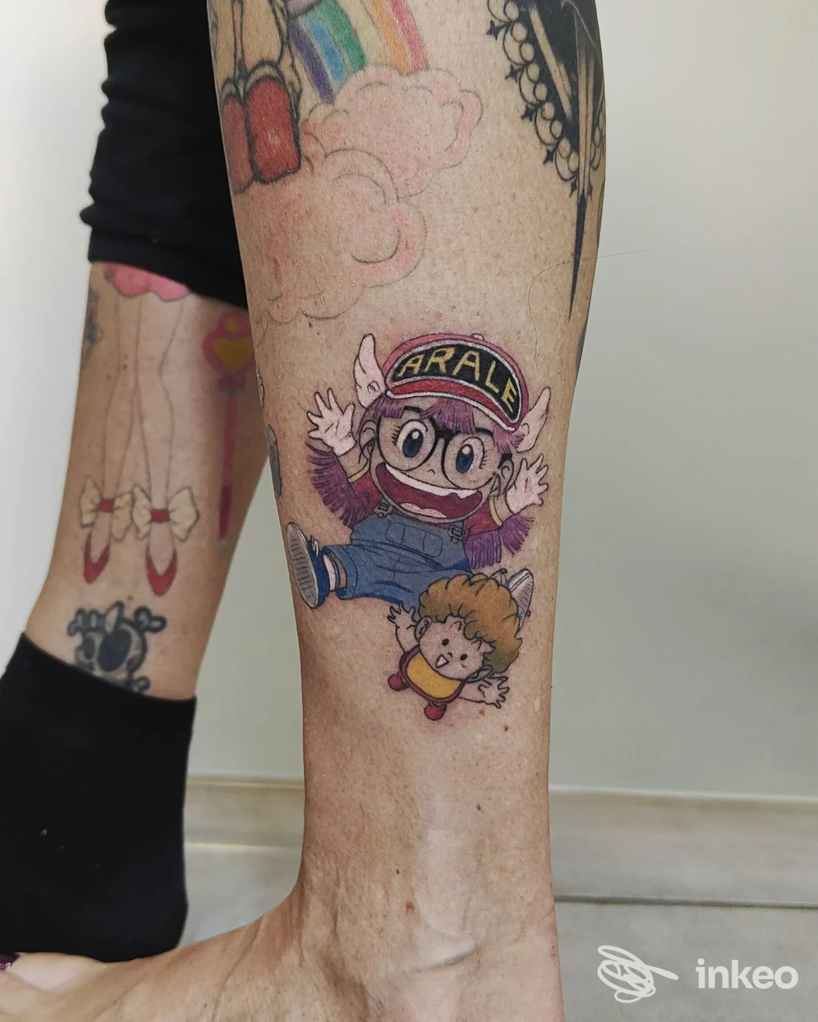 Tatuaggio colorato in stile cartoon sul polpaccio con Arale e un piccolo personaggio, Indelible Art tattoo studio, Roma.