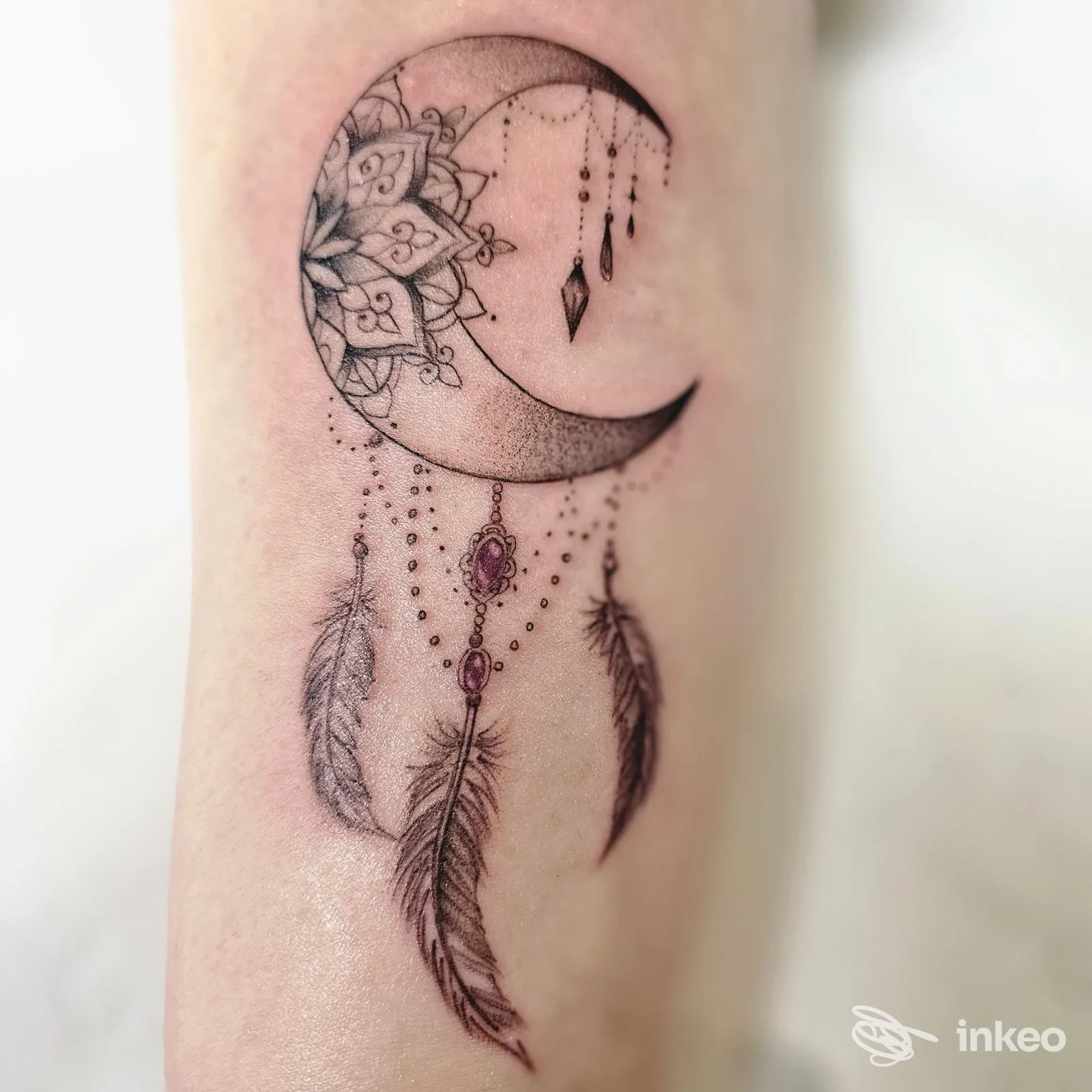 Tatuaggio a mezzaluna ornamentale con pendenti e piume sull'avambraccio, INKancellabile Studio Tattoo - Velletri.