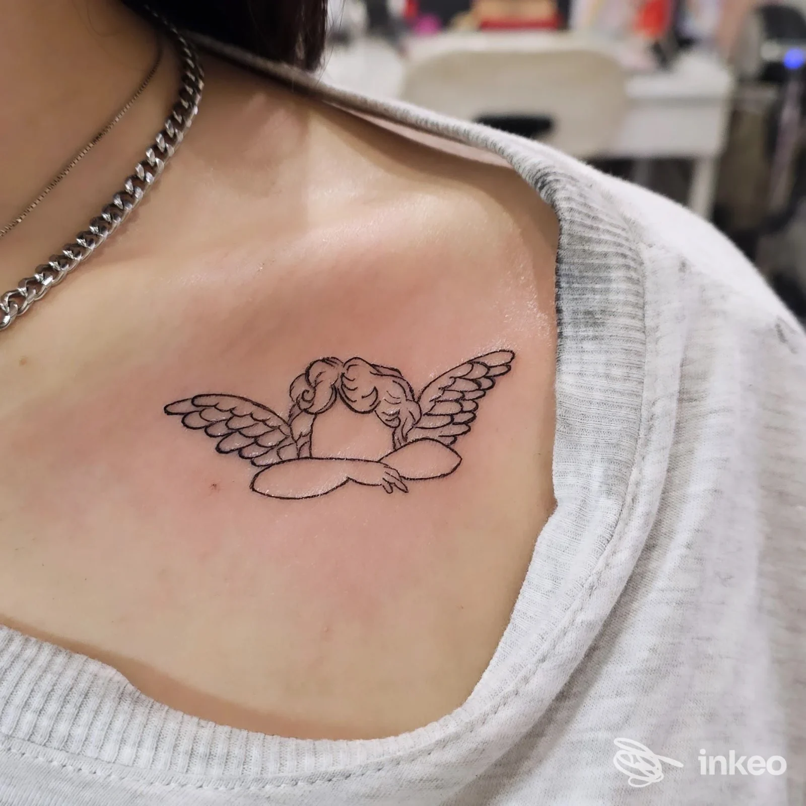 Tatuaggio lineare nero di un angelo sulla clavicola/petto superiore, fotografato presso INKancellabile Studio Tattoo a Velletri.