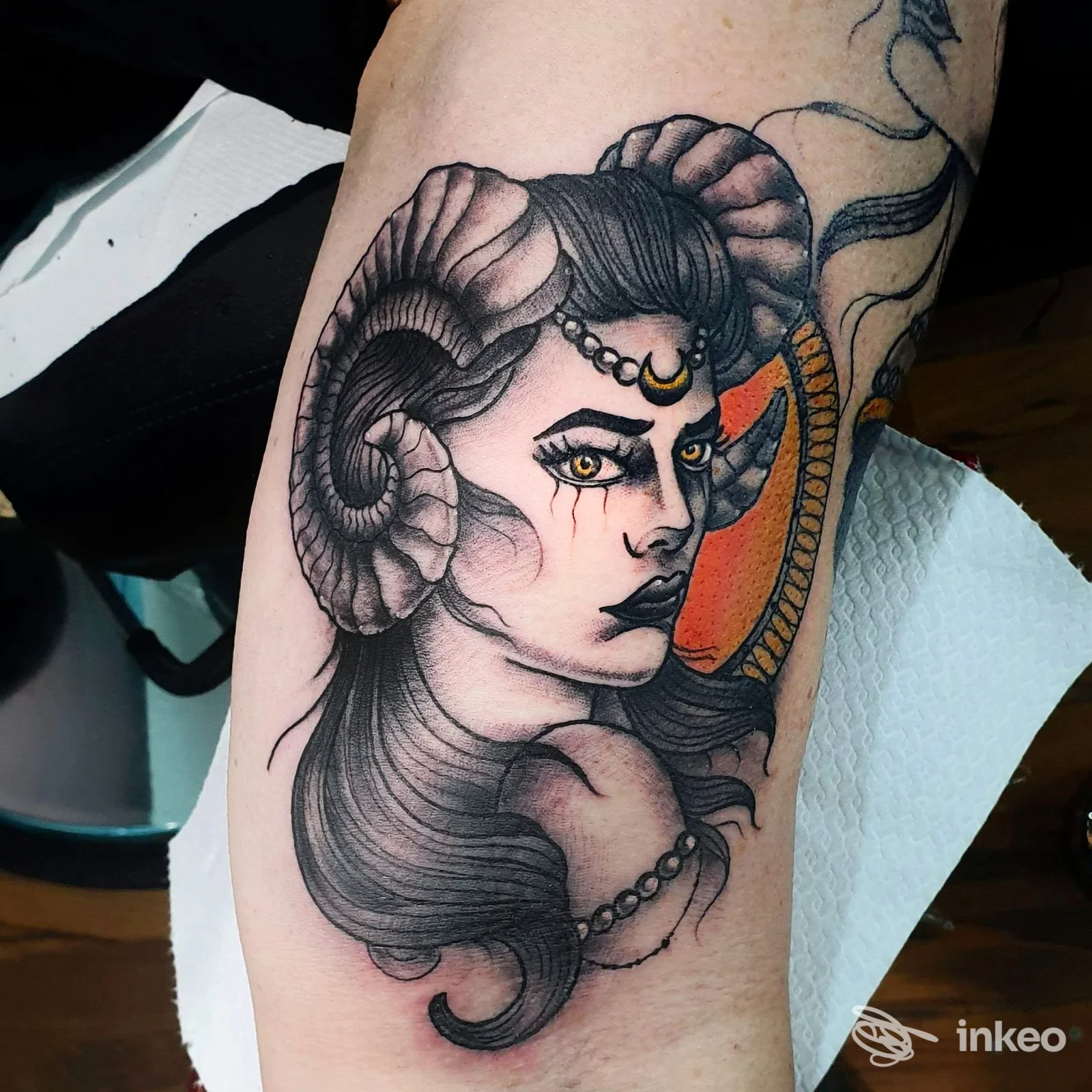 Tatuaggio on avambraccio con volto cornuto e dettagli arancioni, foto fornita da L'altra Metà Tattoo Shop, Gaeta.
