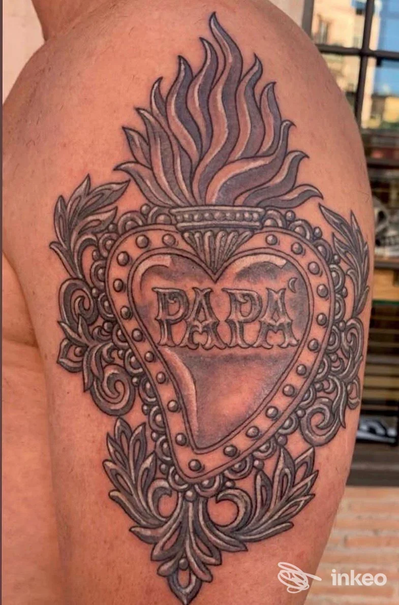 Tatuaggio a cuore fiammeggiante con scritta 'PAPA' sul braccio superiore. Foto inviata da La Bottega dei Tatuaggi, Lido di Ostia.