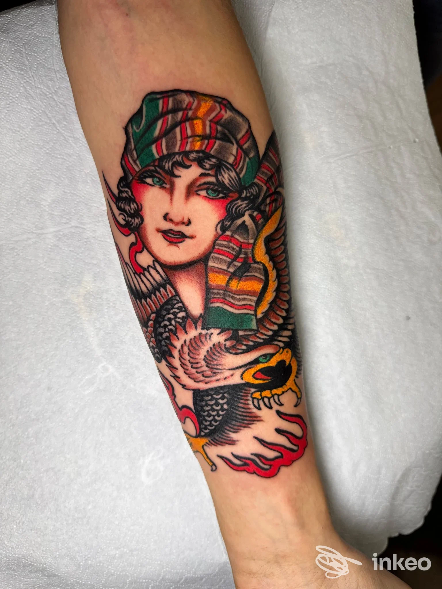 Tatuaggio colorato sull'avambraccio con volto femminile stilizzato e un uccello, realizzato da Lucky Tattoo and Piercing, Roma.
