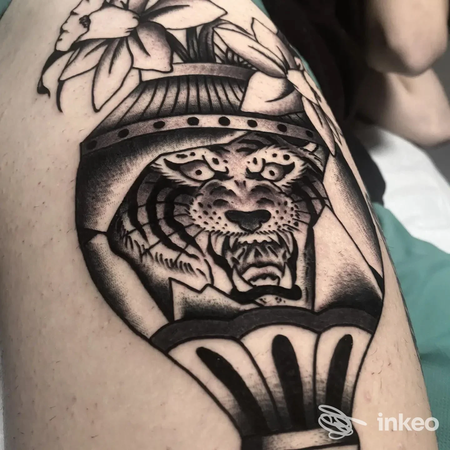 Tatuaggio nero a motivi con testa di tigre e fiori sulla coscia, foto fornita da MASTRO TATTOO, Roma.