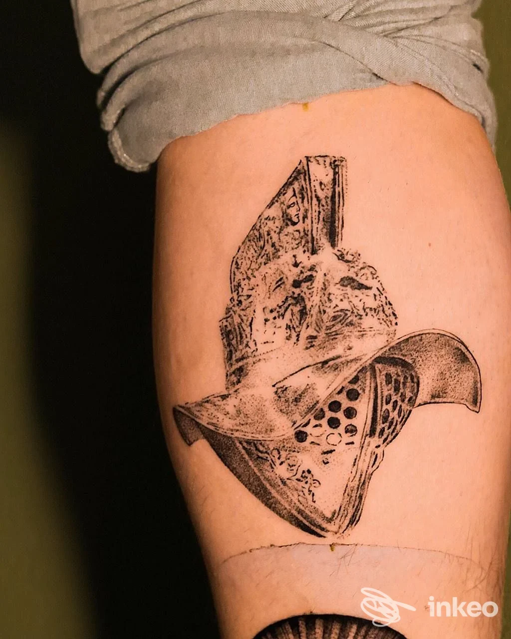 Tatuaggio in stile linework/blackwork raffigurante un elmo, fotografato sulla coscia; immagine fornita da MAXIMO Tattoo Studio, Roma.