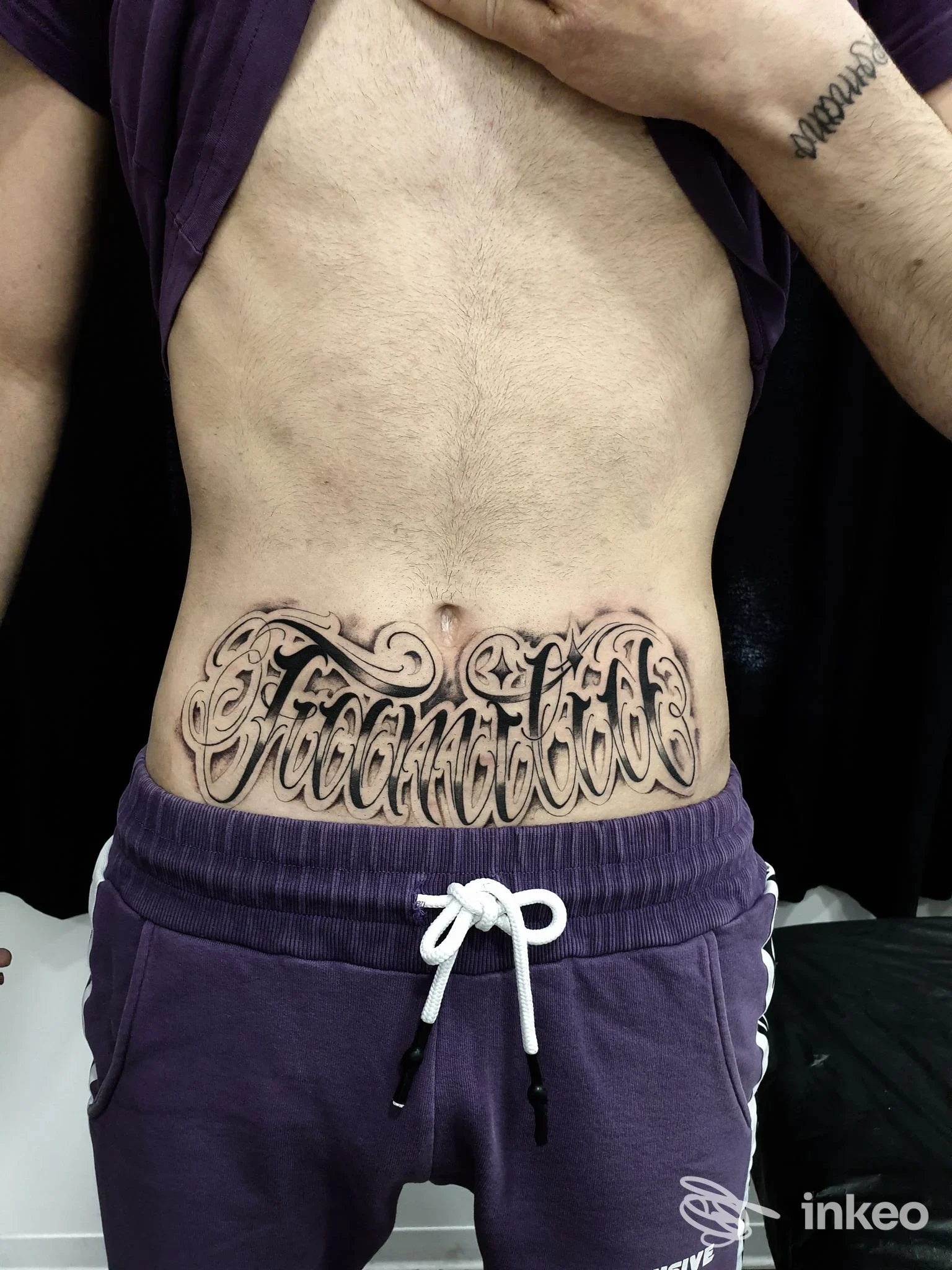 Tatuaggio lettering nero sull'addome inferiore, foto realizzata per MK TATTOO a Roma.