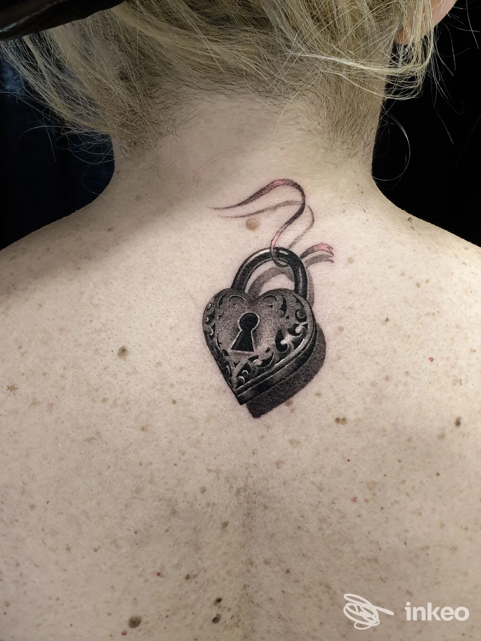 Dettaglio di tatuaggio a lucchetto in bianco e nero sulla nuca di una cliente, fotografato dallo studio MK TATTOO a Roma.