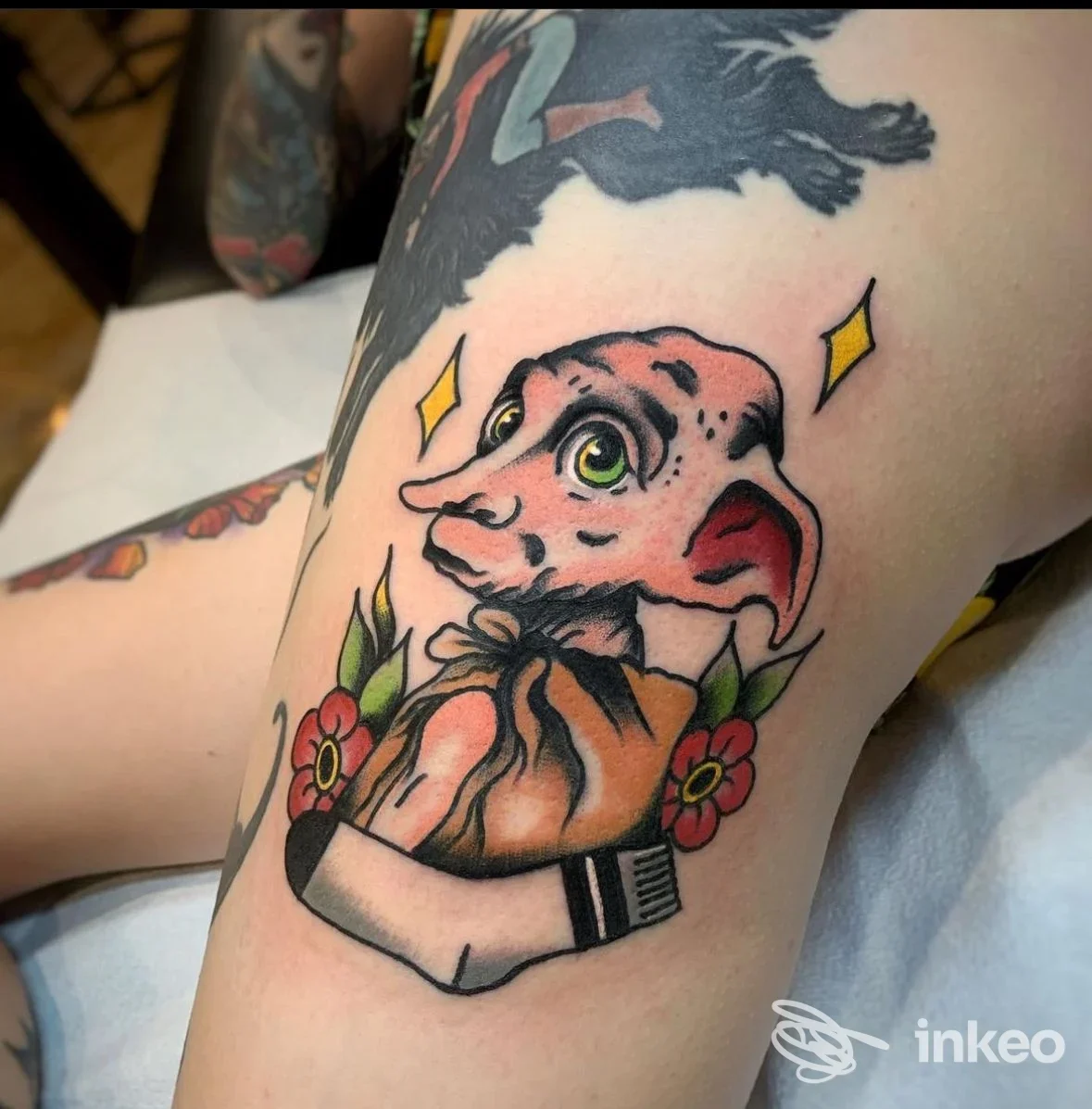 Tatuaggio colorato a Metropolis Shop Roma Tattoo & Barber, Roma: creatura stilizzata con fiori sulla coscia.