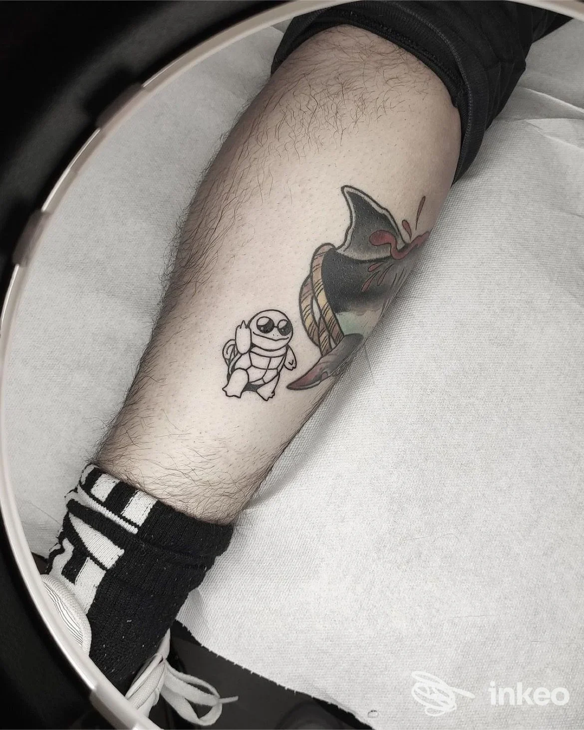 Due tatuaggi visibili su una gamba: un piccolo astronauta bianco e nero e una figura stilizzata più grande, tatuaggi chiaramente visibili sulla pelle.