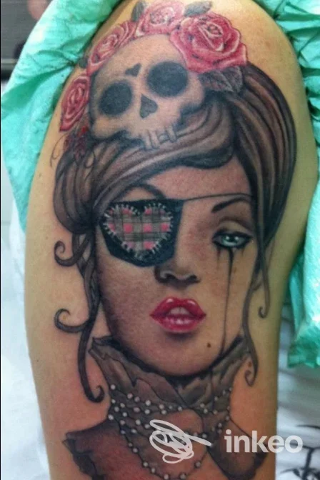 Tatuaggio su braccio con ritratto femminile, benda, teschio e rose, opera fotografata presso Moko Tattoo Studio, Roma.