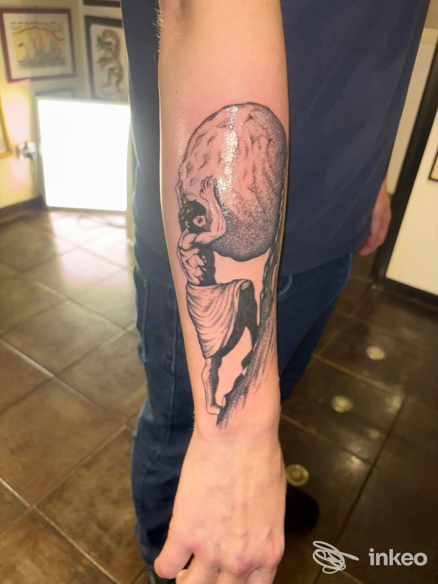 Avambraccio con tatuaggio di Atlante che solleva un globo, fotografia in studio Monkey Business Tattoo Roma, Roma.