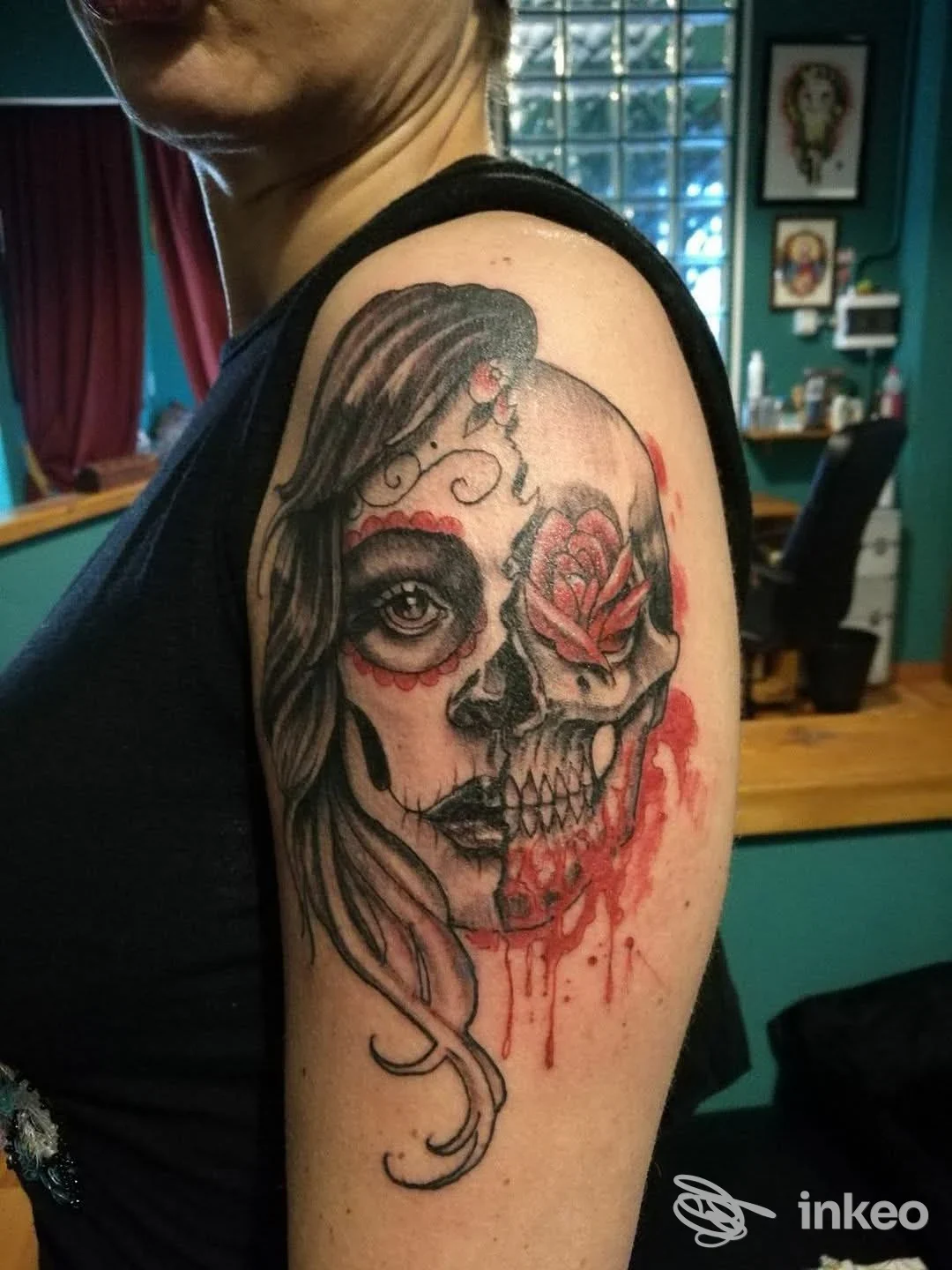 Grande tatuaggio su braccio superiore con volto scheletrico e rosa rossa, foto scattata presso Nightmare Tattoo, Roma.