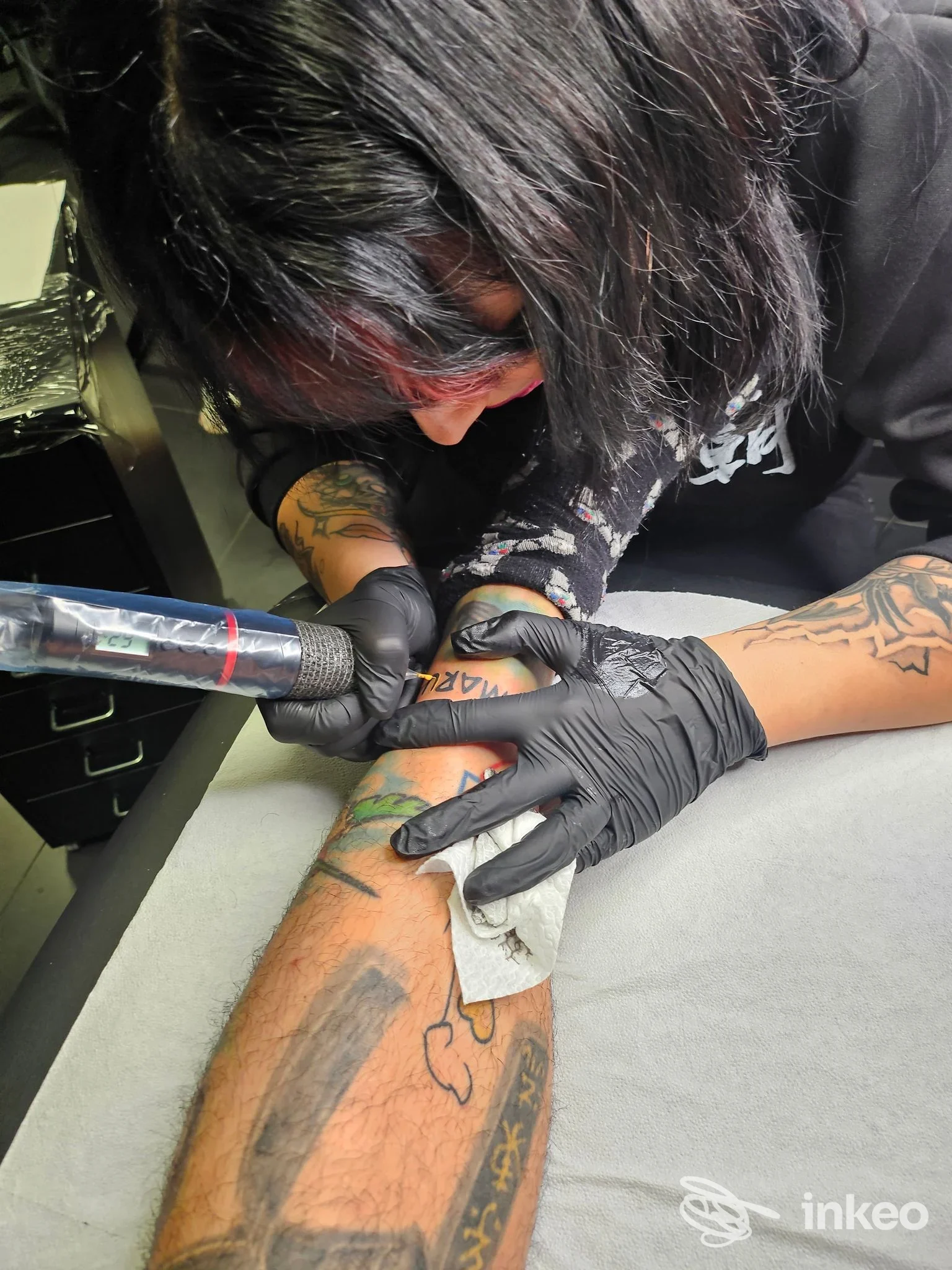 Artista di Nocturnal Tattoos & Spirits a Roma mentre tatua l'avambraccio di un cliente, primo piano sull'area in lavorazione.