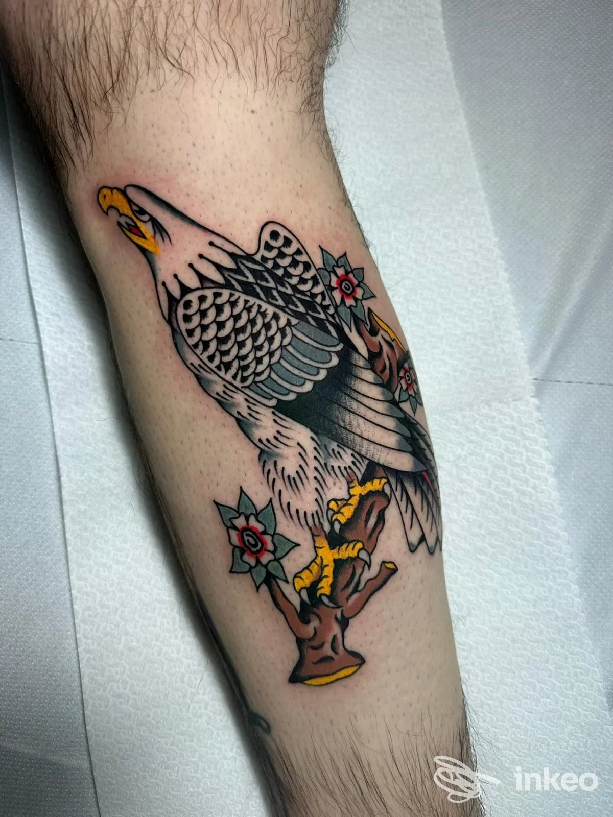 Tatuaggio di un'aquila su ramo con fiori sul polpaccio, realizzato da Roma Classic Tattooing a Roma.