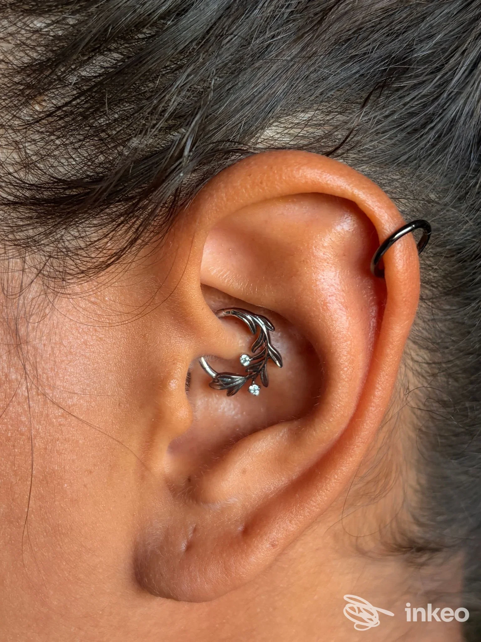 Primo piano di orecchio con due piercing decorativi, fotografia inviata da Perla bodypiercing & jewelry, Roma.