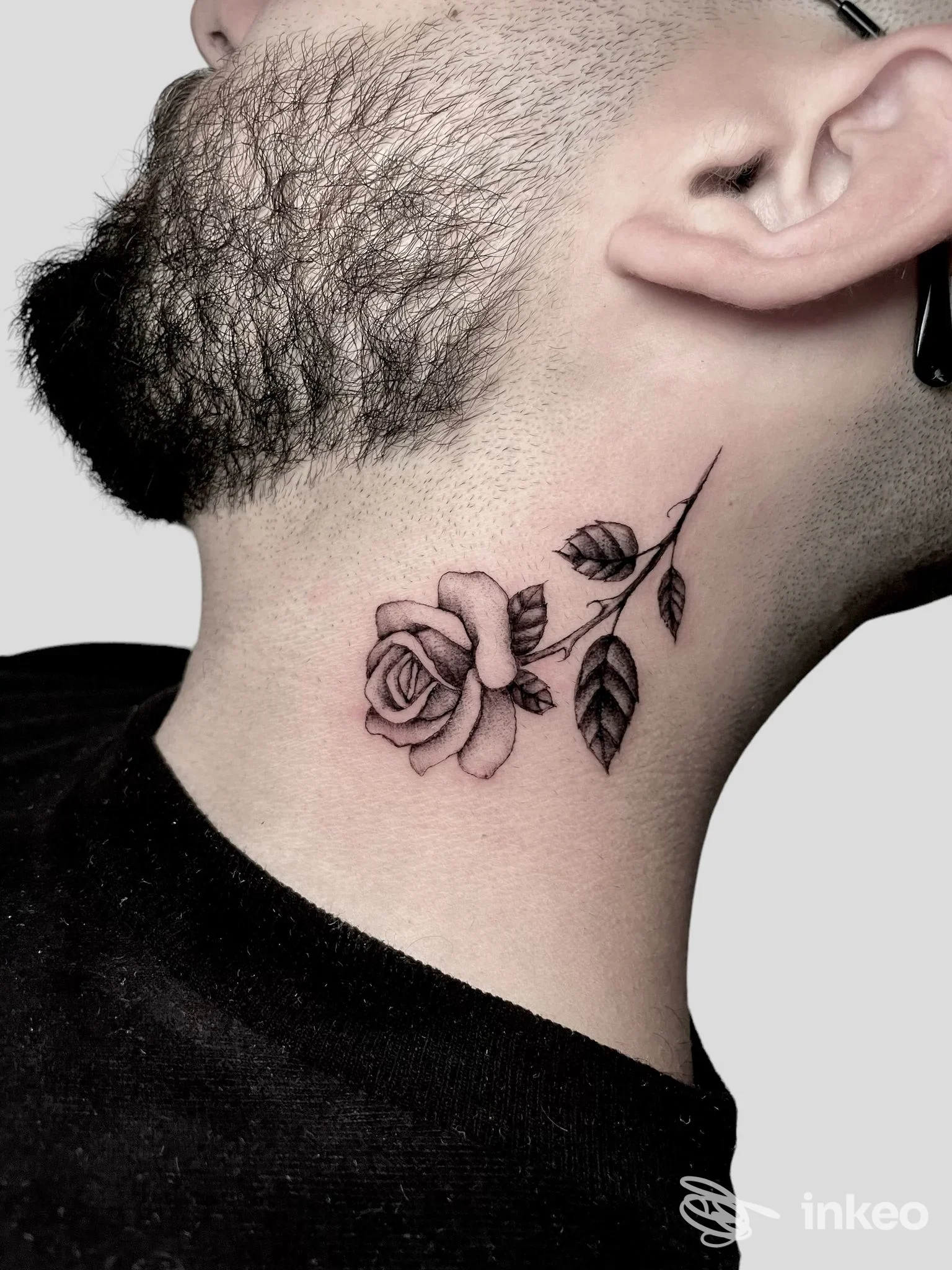 Primo piano laterale di un collo maschile con tatuaggio a rosa; lavoro eseguito da One More Tattoo, Roma.