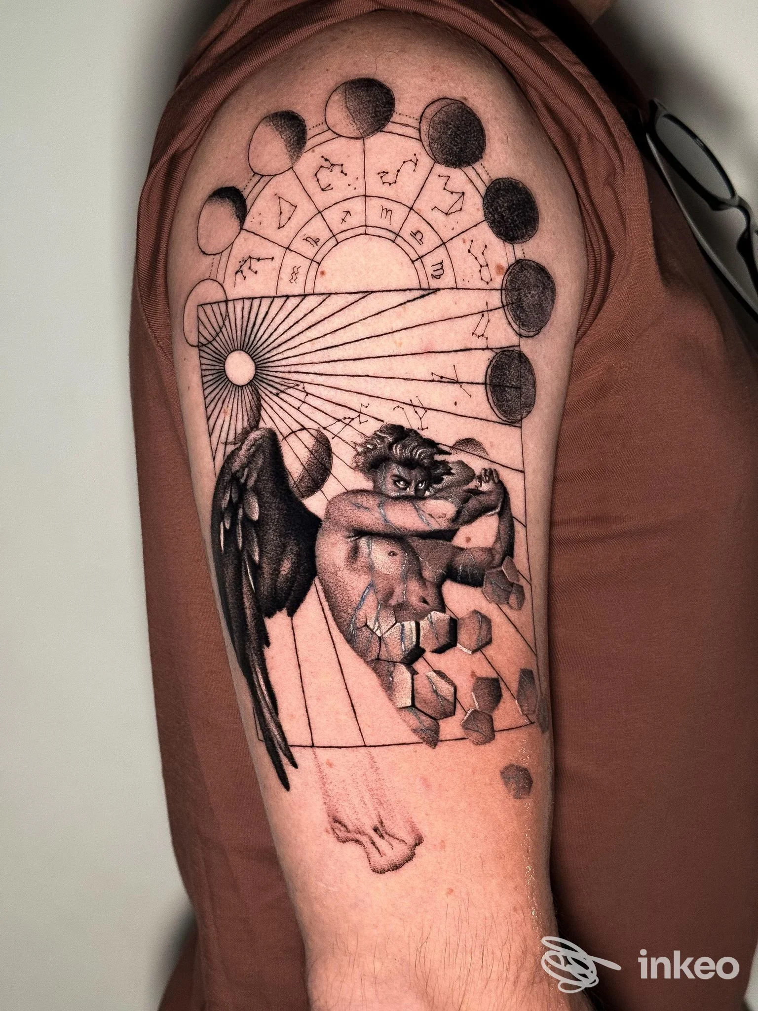 Tatuaggio sul braccio superiore con fasi lunari, elementi geometrici e figura angelica, lavoro di Sangue Blu Tattoo Shop, Roma.