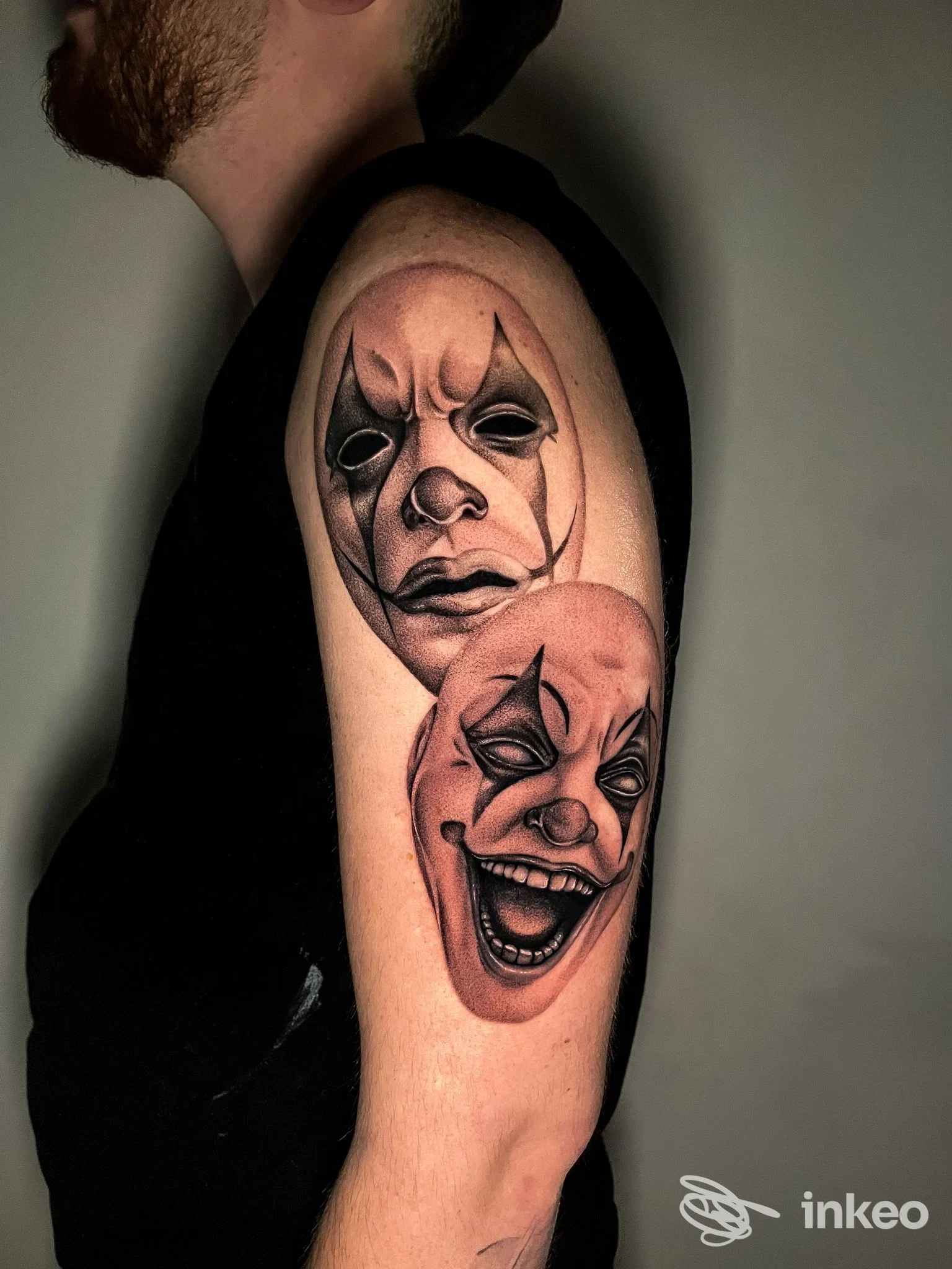 Due volti da clown tatuati sull'alto del braccio, foto inviata da Sangue Blu Tattoo Shop, Roma.