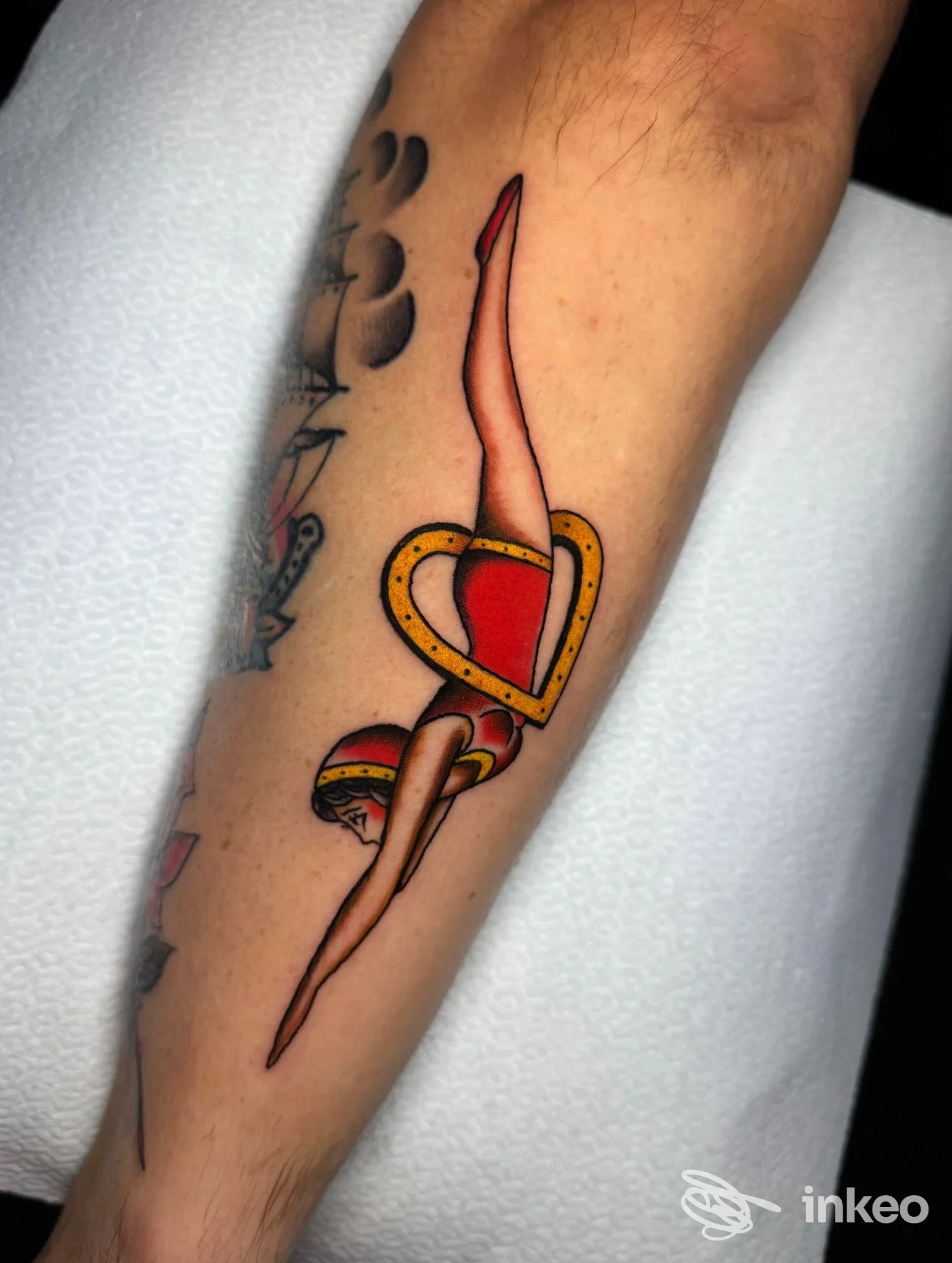 Tatuaggio tradizionale su avambraccio: tuffatrice stilizzata dentro un cuore giallo e rosso. Shovel Barbershop & Tattoo, Roma.