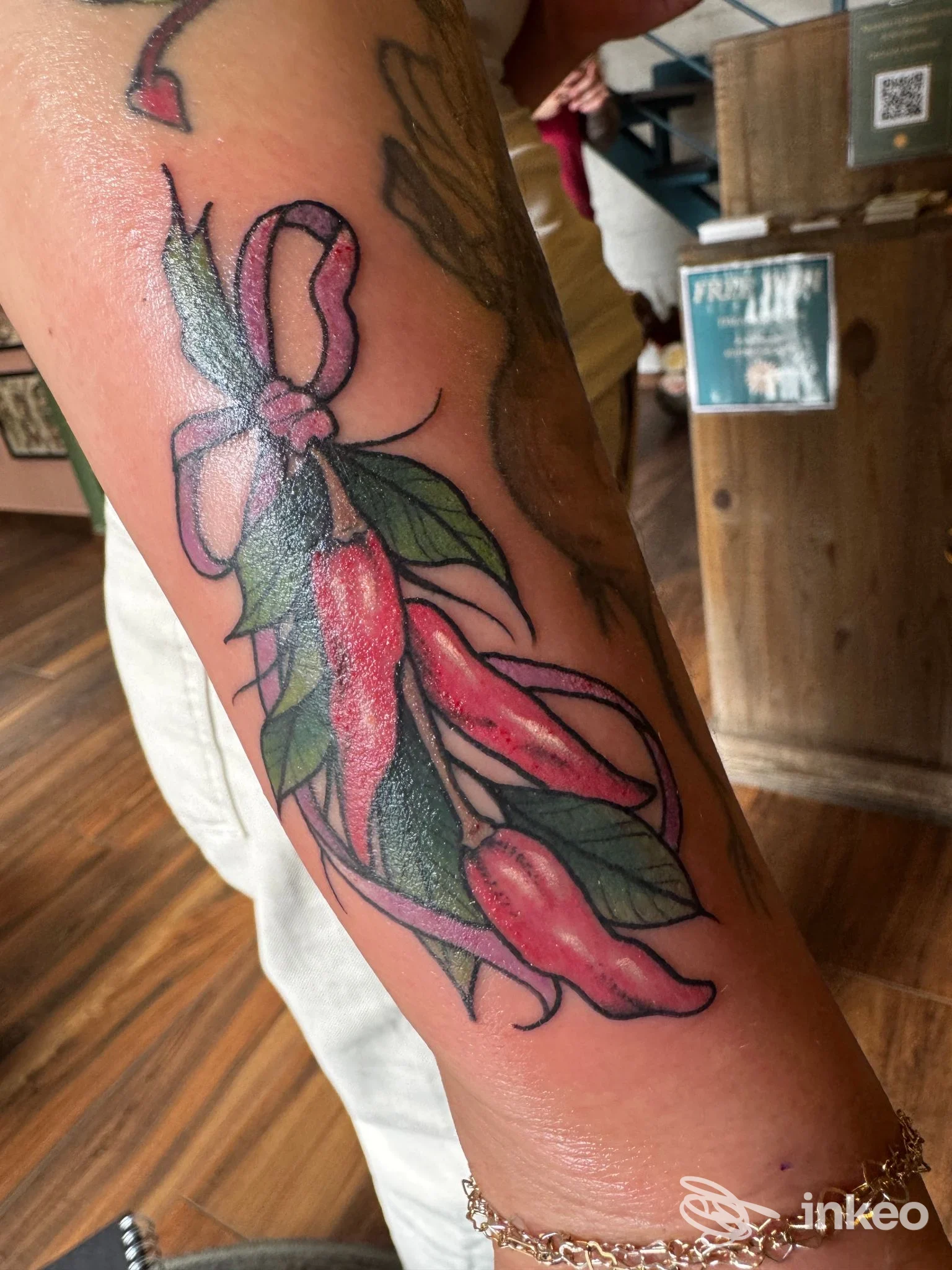 Tatuaggio colorato a fiori e fiocco sull'avambraccio, foto scattata presso Sin Dolores Tattoo Studio a Roma.