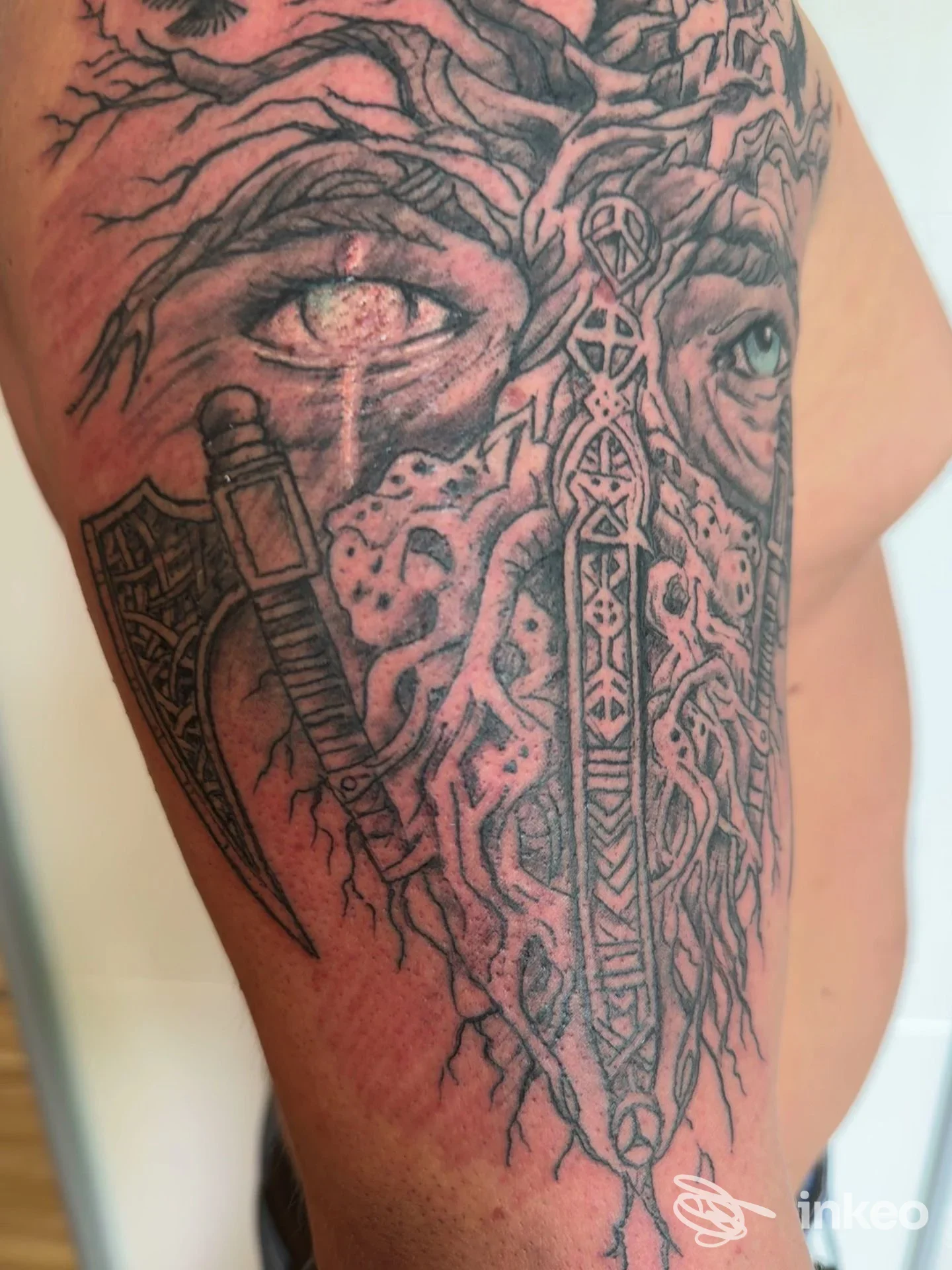 Tatuaggio in bianco e nero raffigurante un volto intrecciato a radici e un pugnale sul braccio, Sinapsy Tattoo & Piercing, Colleferro Scalo.