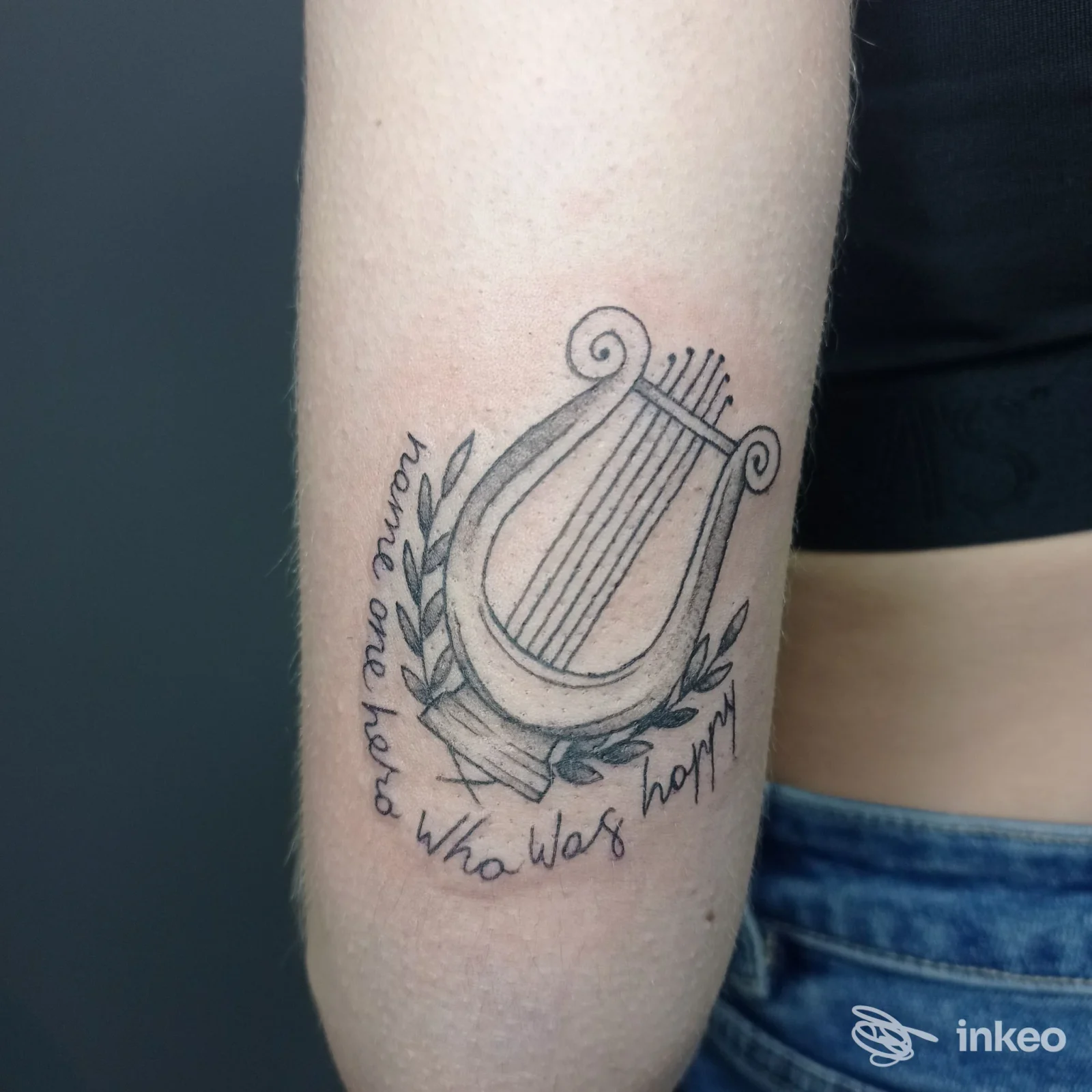 Tatuaggio di lira stilizzata con ramoscello e scritta sul avambraccio interno, realizzato da Stanza 707 Tattoo Studio a Ceprano.