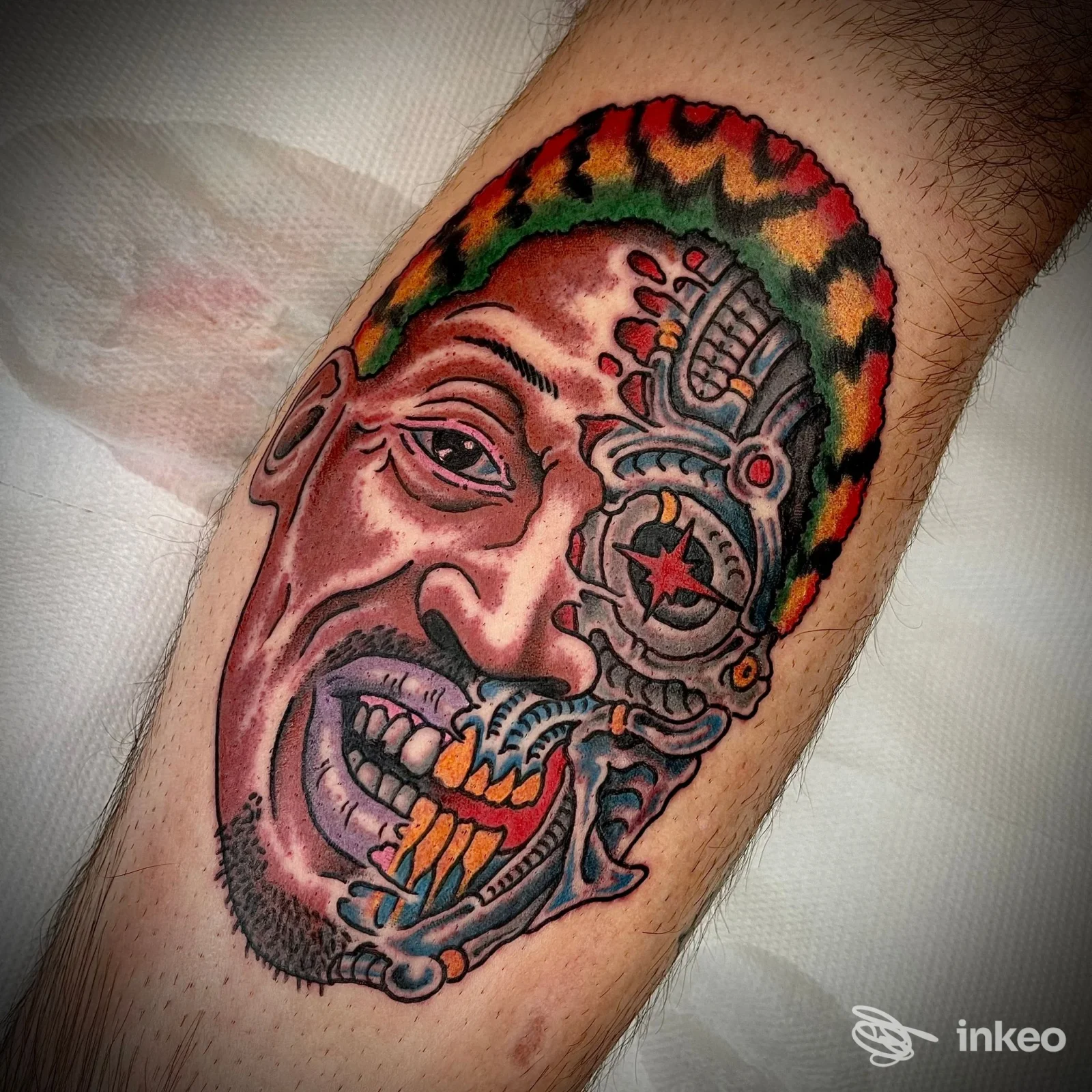 Tatuaggio colorato su polpaccio raffigurante un volto biomeccanico, Swan Song Tattoo - Trastevere, Roma.