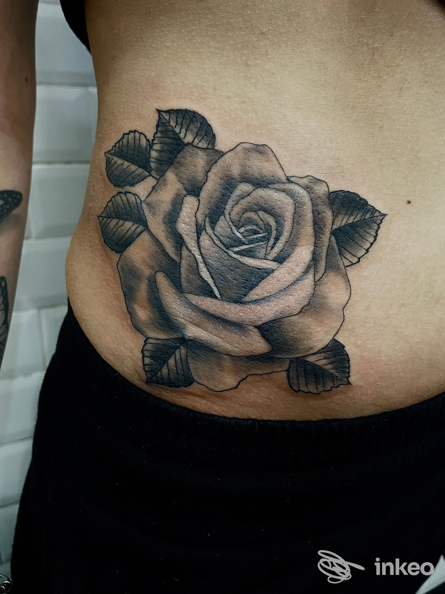 Rosa in bianco e nero tatuata sull'addome/fianco; lavoro eseguito da TATTOO SKILL ROMA, Roma.