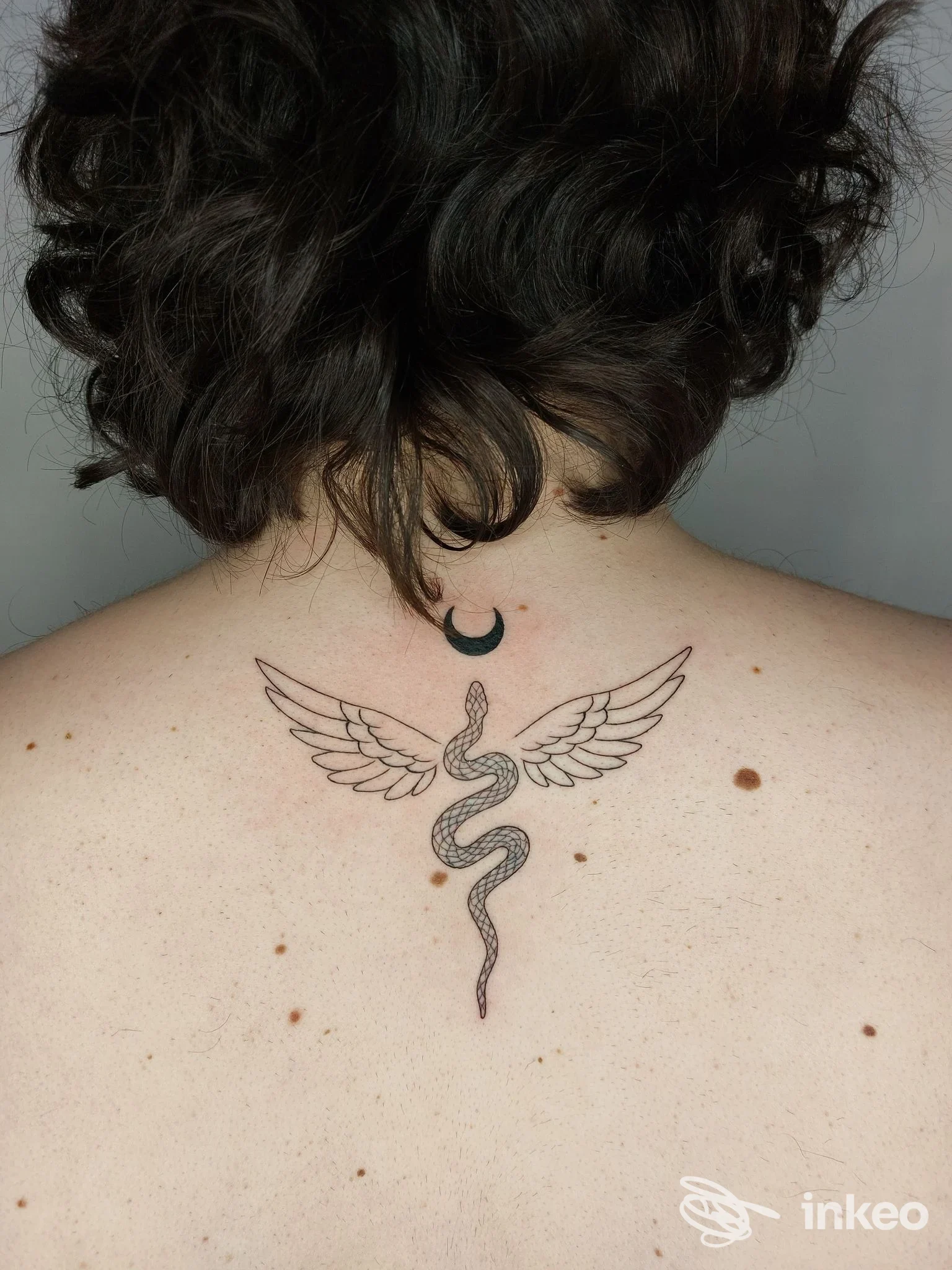 Tatuaggio di serpente alato con luna crescente sulla parte alta della schiena, foto inviata dallo studio Tattoo & Piercing Sweet Mamba, Roma.
