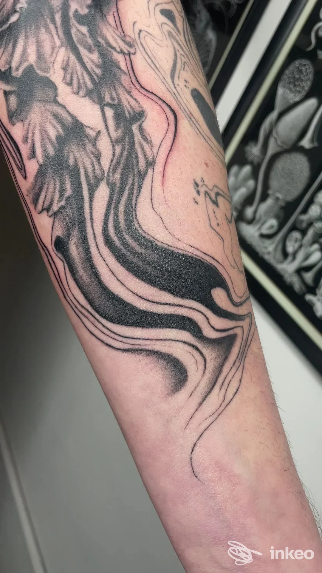 Primo piano di un avambraccio tatuato con motivi fluidi in nero e sfumature, scatto nello studio Tattoo & Piercing Sweet Mamba Roma, Roma.