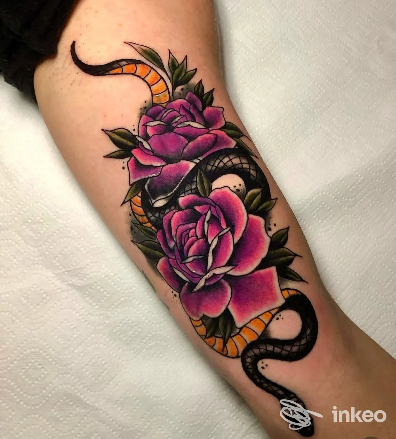 Tatuaggio su avambraccio con due rose viola e un serpente nero/arancione, lavoro fotografato e postato dallo studio TATTOO49 Roma.