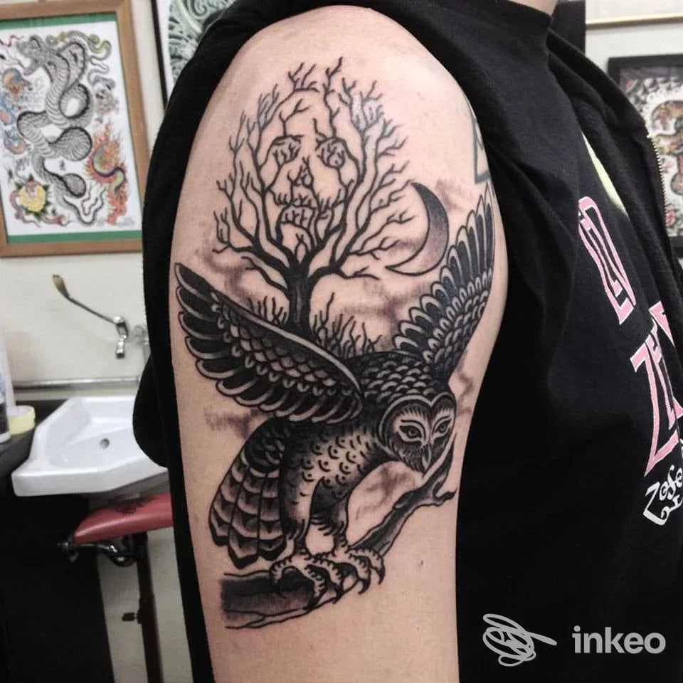 Tatuaggio su braccio superiore con gufo in volo e albero stilizzato, foto realizzata da Underdog Tattoo Roma, Roma.