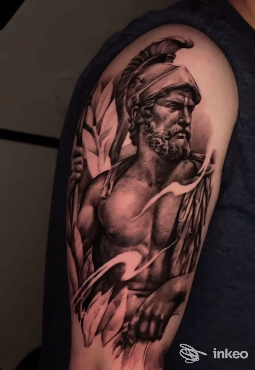 Tatuaggio realistico in bianco e nero su spalla/alto braccio raffigurante un guerriero classico, realizzato da Vesta Tattoo Atelier a Roma.