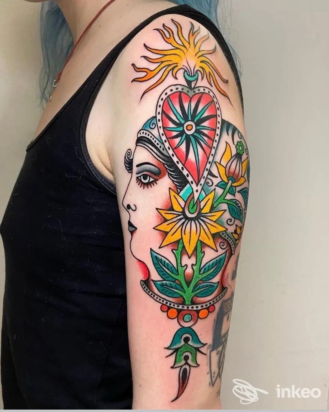 Tattoo colorato sull'avambraccio di una persona: motivi floreali e decorativi che si estendono dalla spalla al braccio, senza testo promozionale visibile.