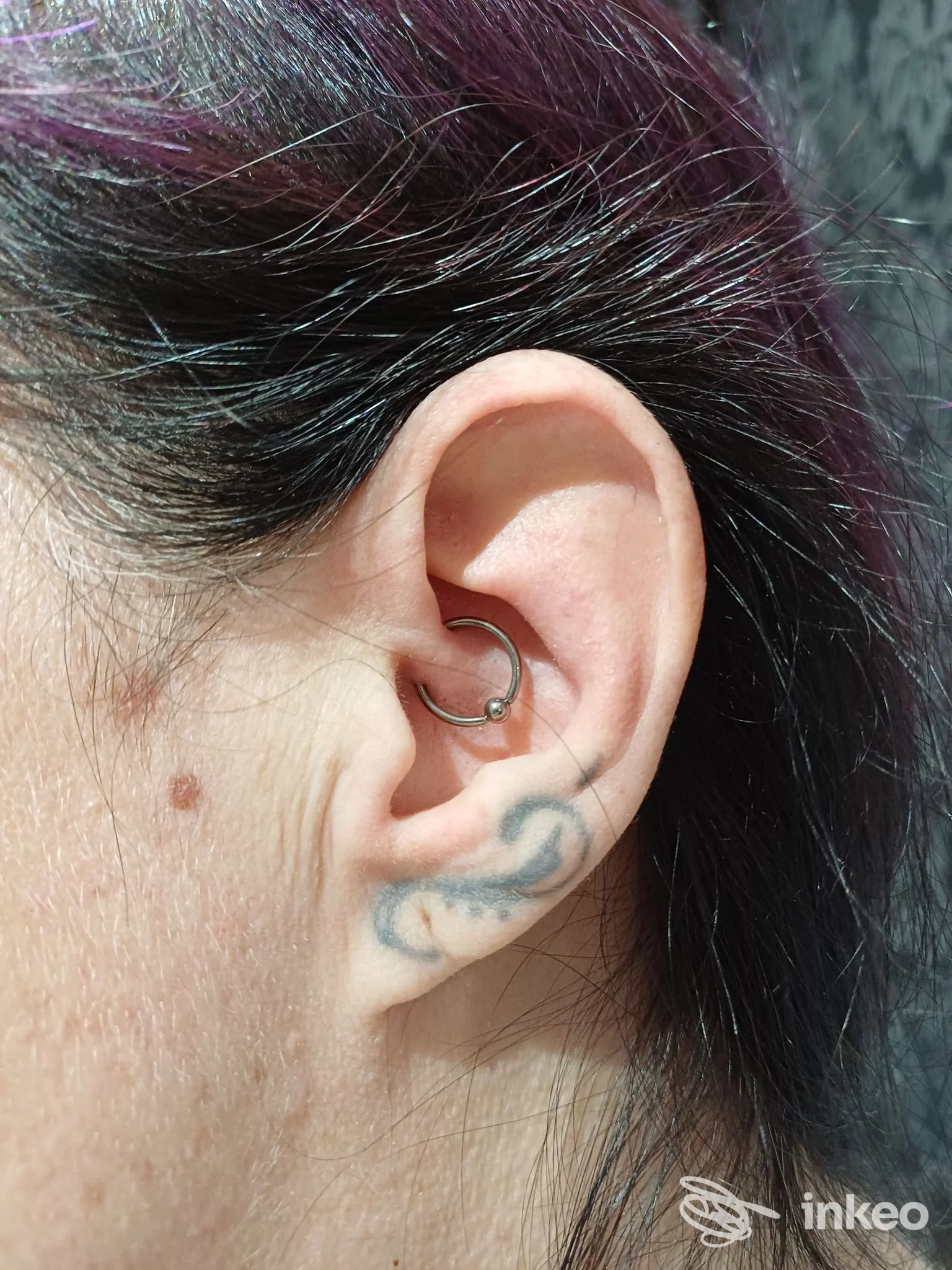 Primo piano di orecchio con piercing e piccolo tatuaggio, foto fornita da The New Family Tattoo Roma.