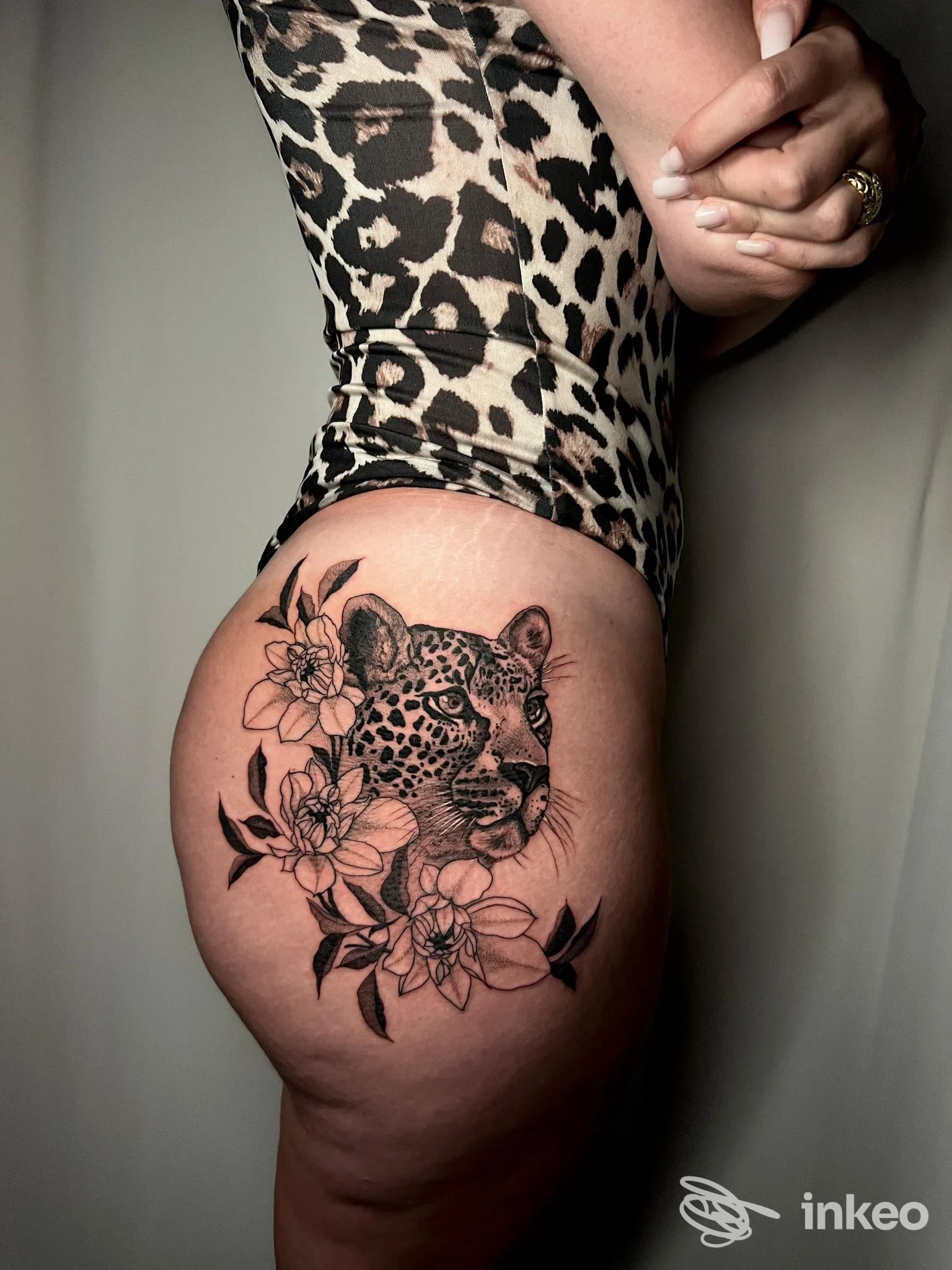 Tatuaggio realistico in bianco e nero di testa di leopardo e fiori sul fianco, pubblicato dallo studio Ultimi Romantici Tattoo a Roma.