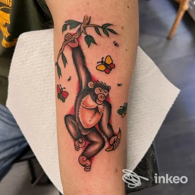Tatuaggio su avambraccio con una scimmia appesa a un ramo e farfalle, foto caricata dallo studio Ultimi Romantici Tattoo, Roma.