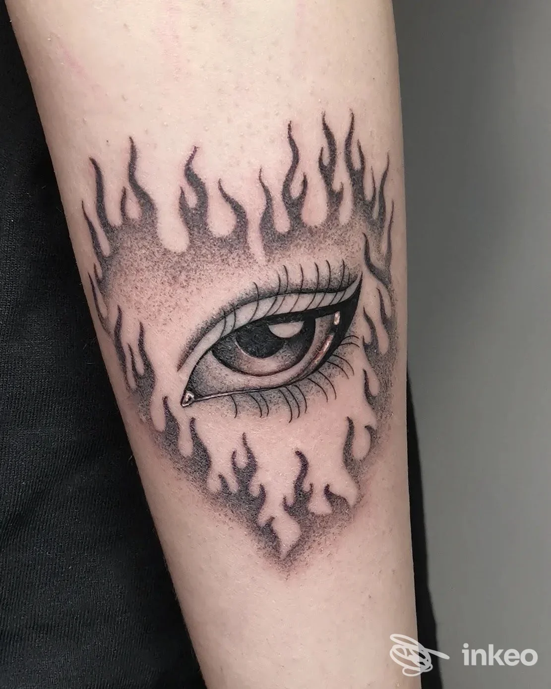 Tatuaggio a occhio circondato da fiamme in nero e grigio sull'avambraccio, Xaba Tattoo Studio a Fondi.