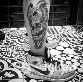 Tatuaggio realistico con teschio e gufo sul polpaccio, foto inviata dallo studio juanita tattoo a Roma.