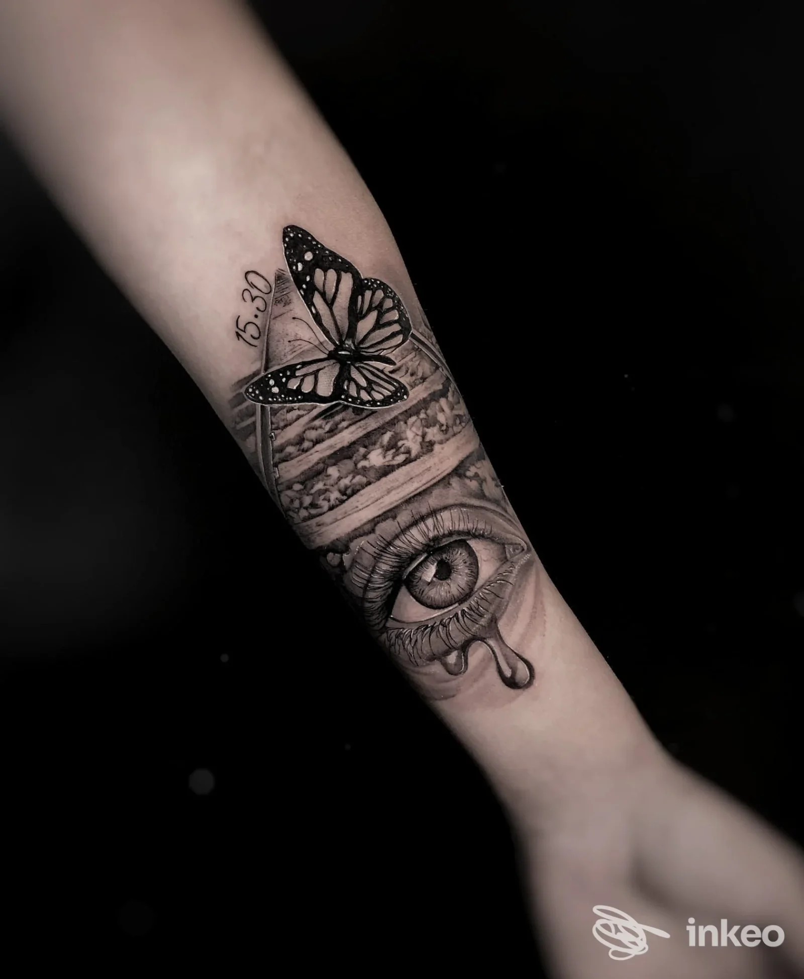 Tatuaggio in bianco e nero su avambraccio con farfalla e occhio stilizzato, foto fornita da magorium tattoo studio, Roma.