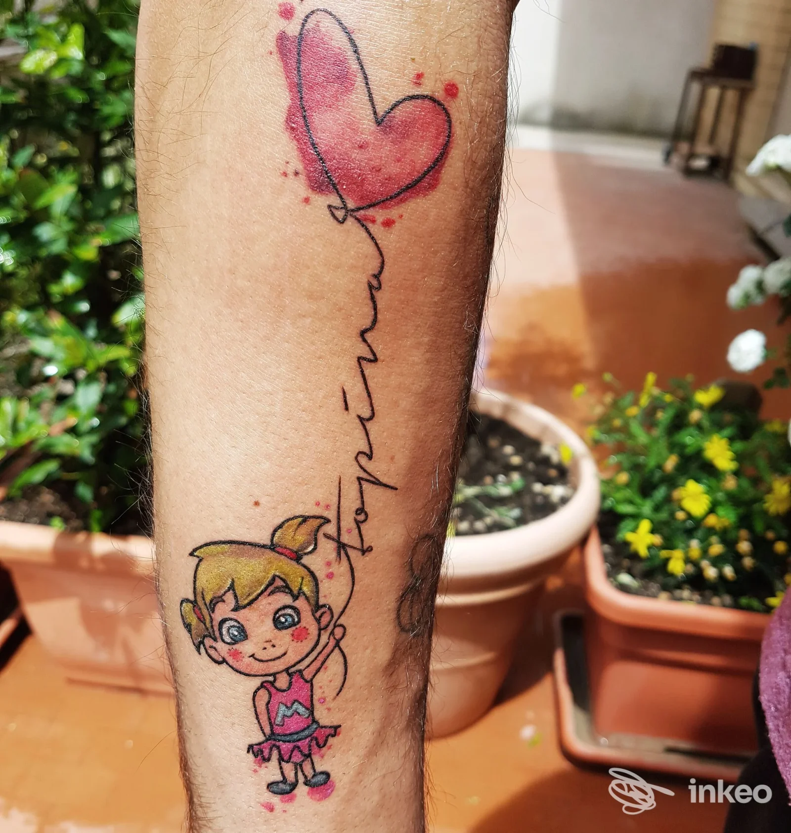 Tatuaggio colorato sull'avambraccio con bambina in stile cartoon che trattiene un palloncino a forma di cuore. 8th SIN TATTOO, Lido di Ostia.