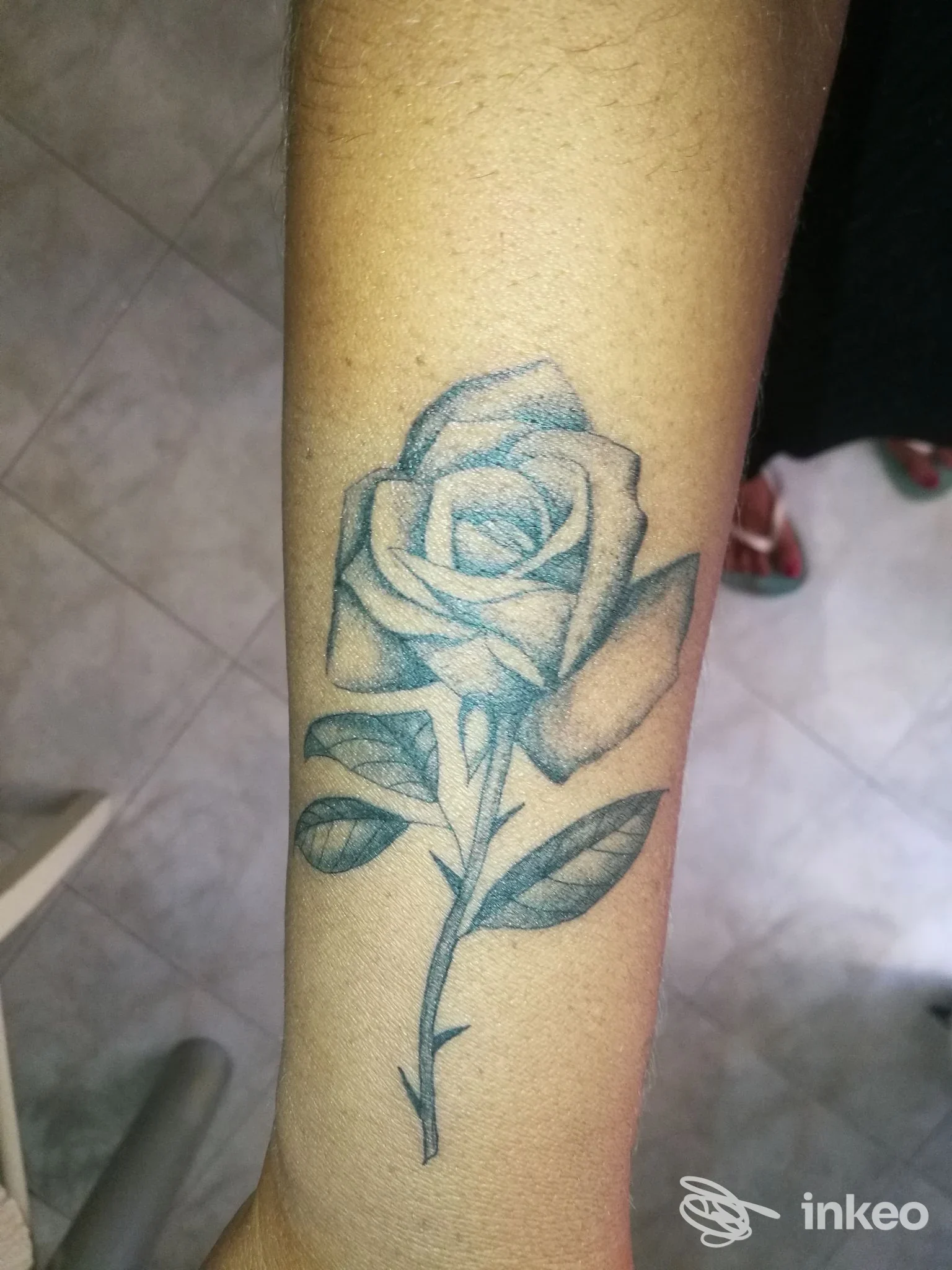 Tatuaggio a forma di rosa in nero/grigio sul lato interno dell'avambraccio, foto fornita da Alessio Lala Tattoo Studio, Roma.