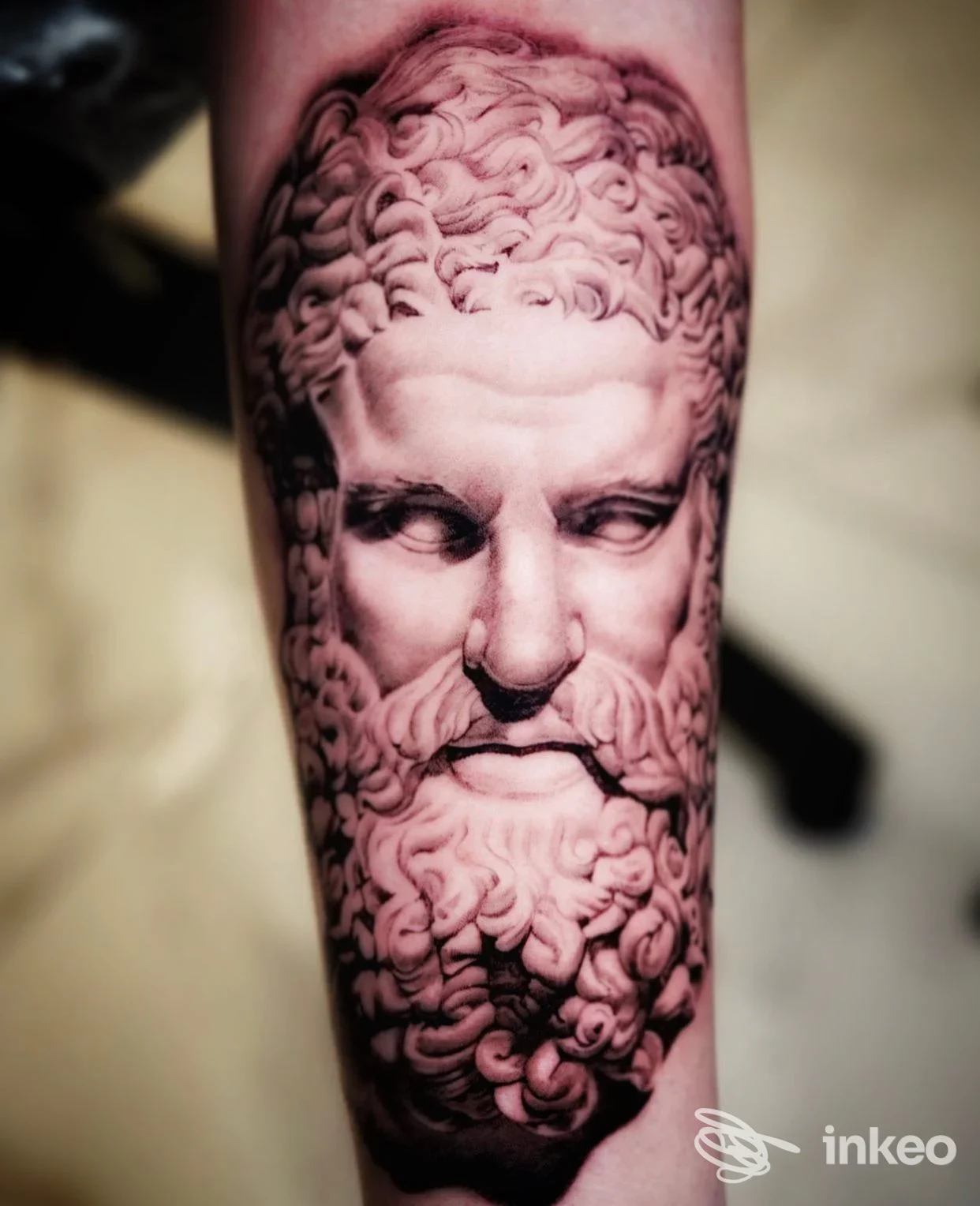Tatuaggio realistico in bianco e nero di un volto-scultura sull'avambraccio, Alessio Lala Tattoo Studio, Roma.